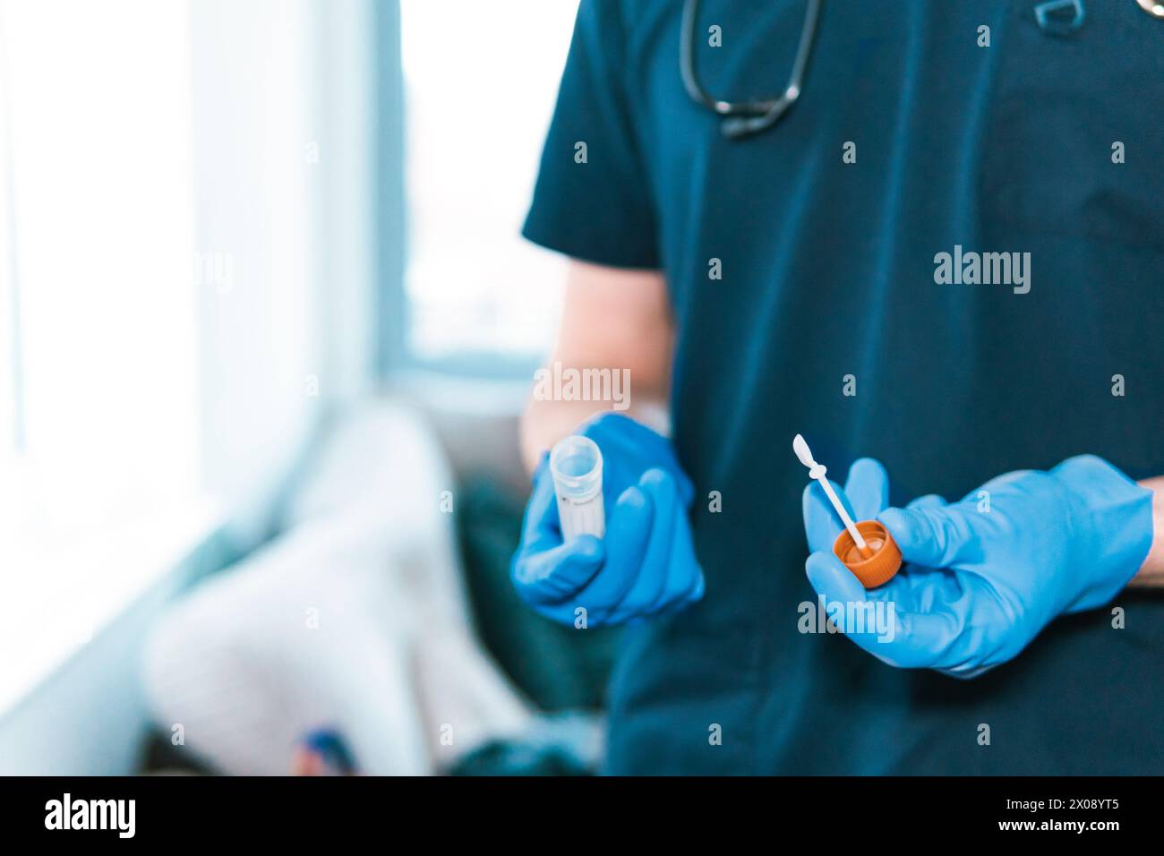 Nahaufnahme der Hände eines anonymen Arztes, mit blauen Handschuhen, die einen sterilen Probenbehälter und einen Applikator halten Stockfoto