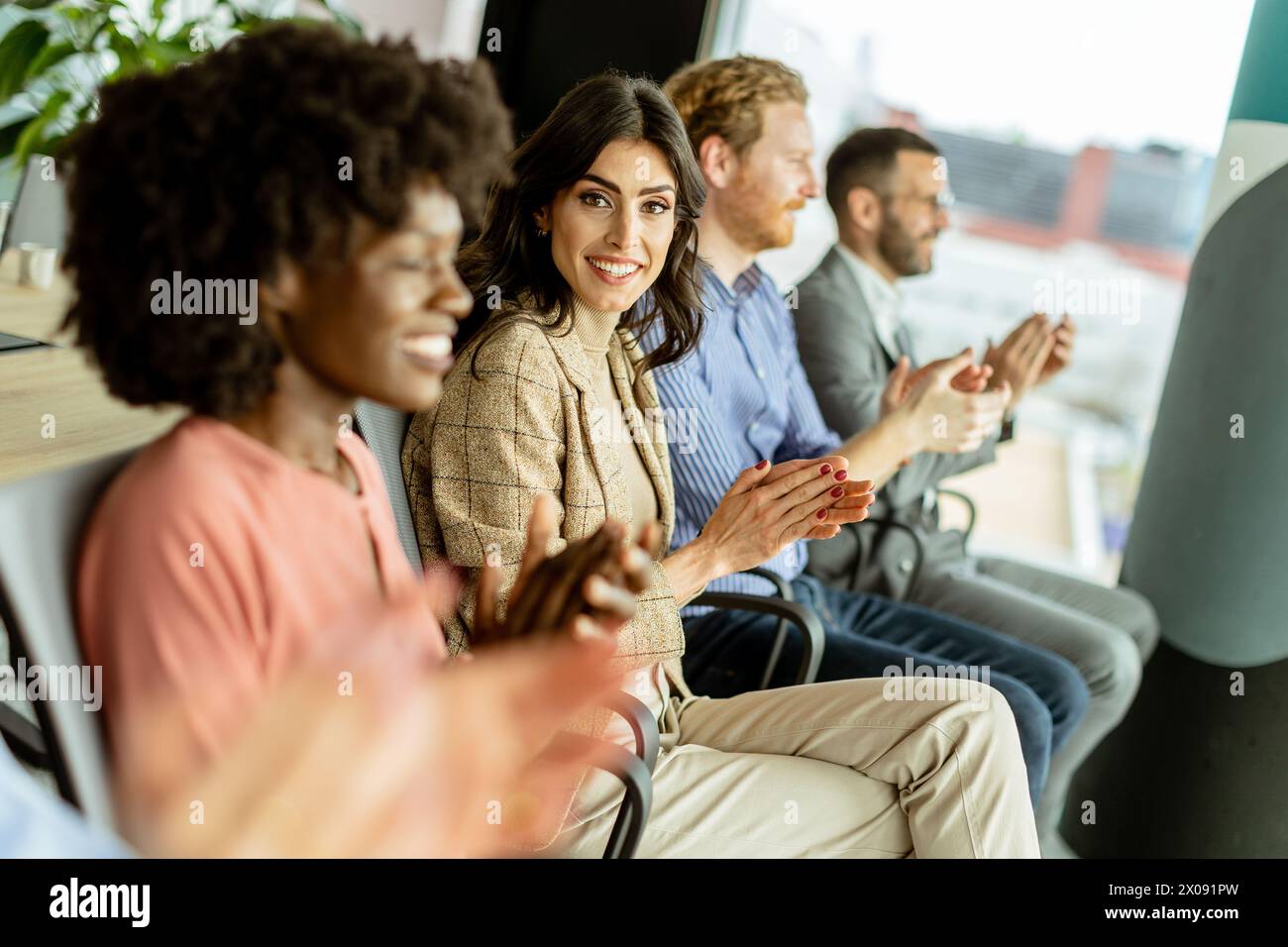 Die lächelnde Frau führt eine Runde Applaus mit Gleichaltrigen und teilt einen Moment der Freude Stockfoto