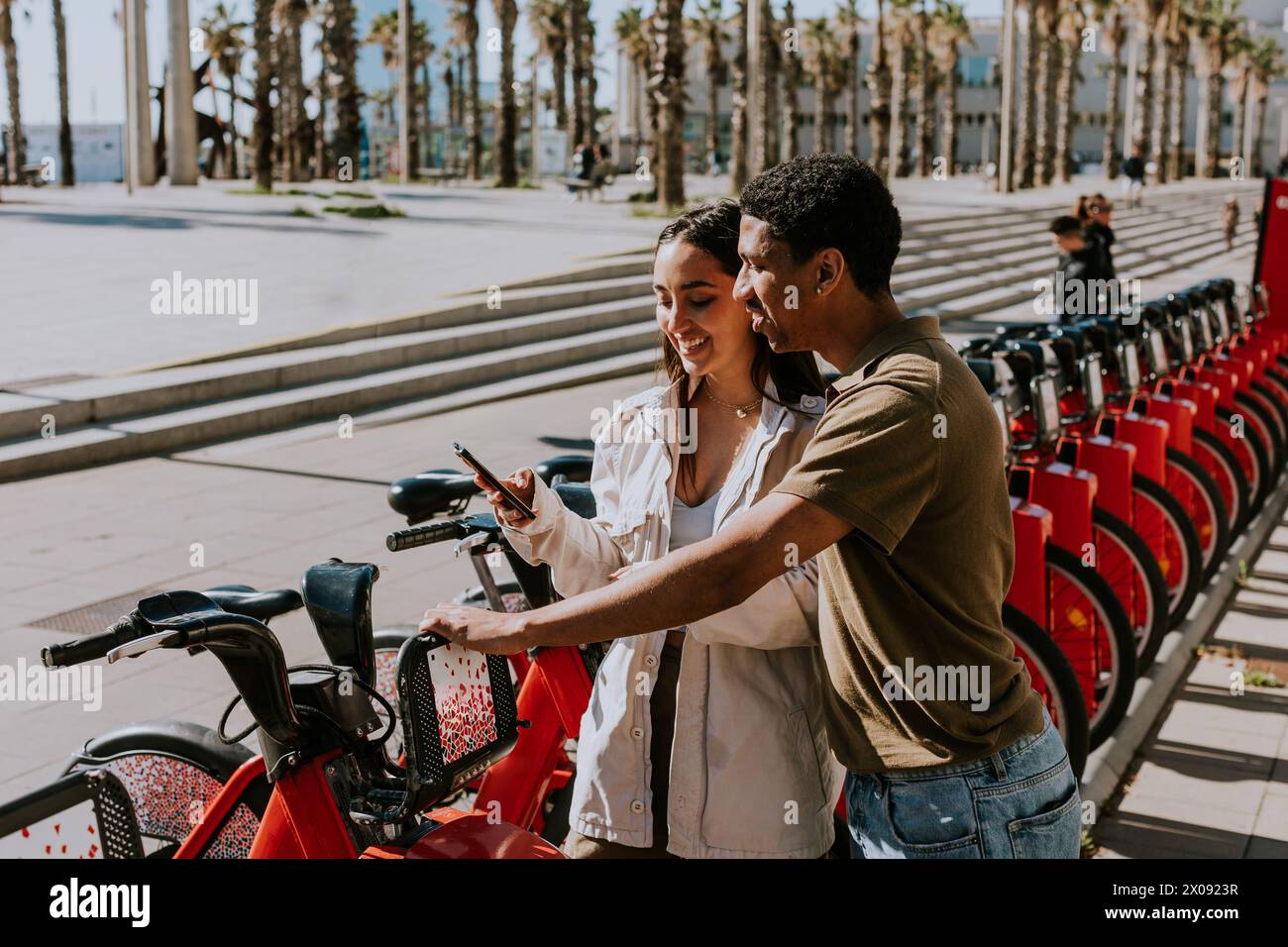 Junge Paare, die einen luftigen Tag mit Fahrrädern von einer Verleihstation in Barcelona verbringen. Stockfoto