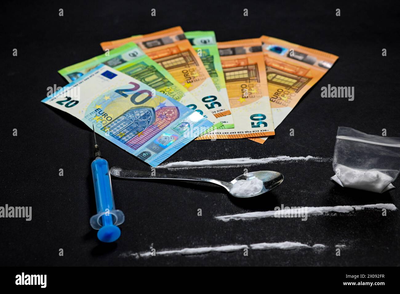 Kokain mit Spritze und Löffel, Beutel voller Heroin auf schwarzem Hintergrund und Stapel Euro-Geld. Stoppen Sie Drogen und sucht. Stockfoto