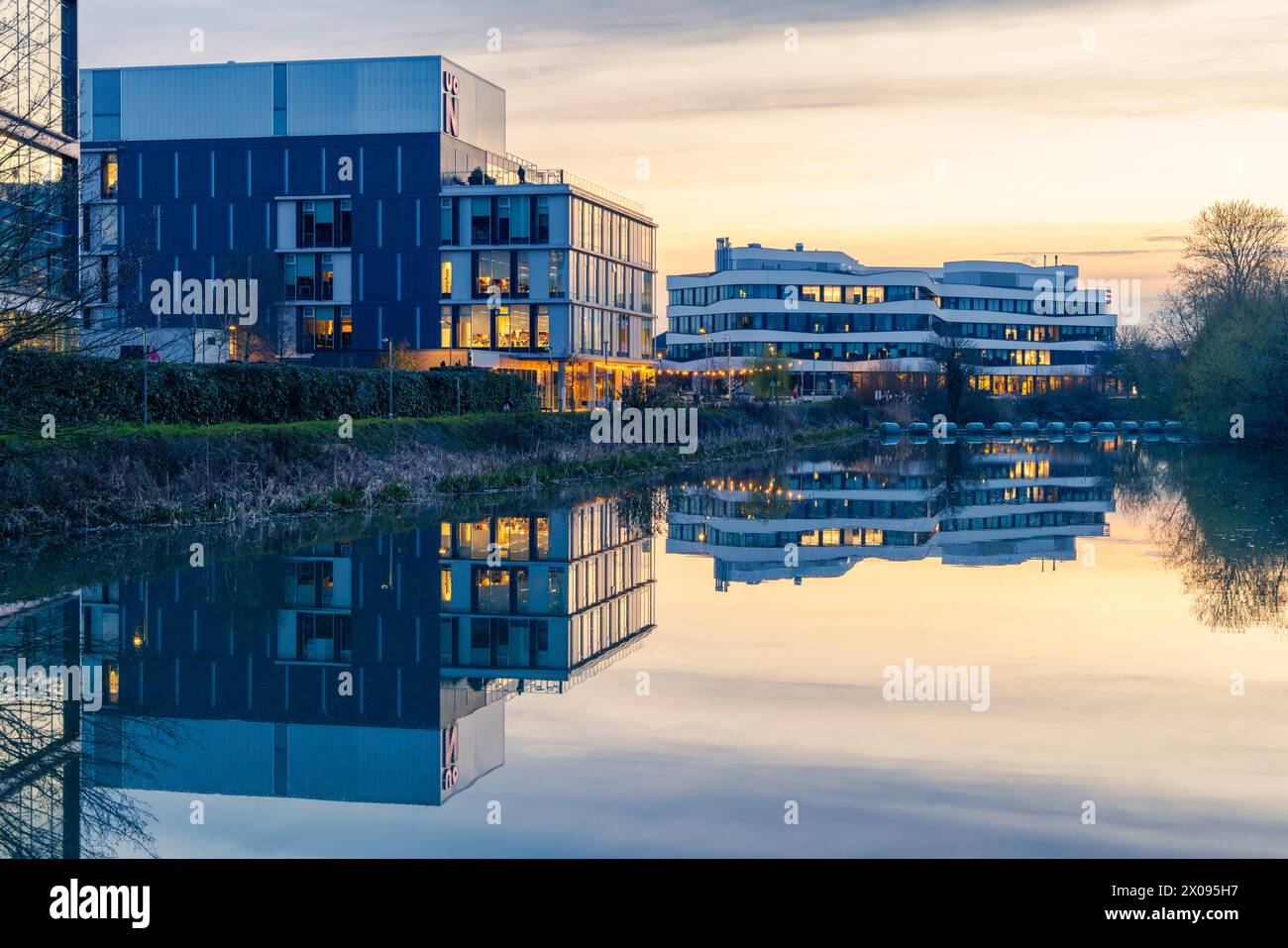 Northampton, Northamptonshire, Großbritannien - April 2023: Die Gebäude des Northampton University Waterside Campus spiegeln sich bei Sonnenuntergang im Fluss Nene. Stockfoto