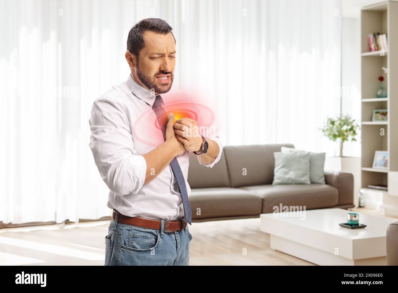 Geschäftsmann in einem Wohnzimmer hält seine Brust in Schmerz zu Hause, Gesundheit Thema Konzept Stockfoto