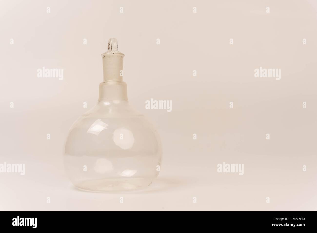 Eine durchsichtige Glasflasche mit Stopfen, ideal für chemische Experimente, wird auf einem sauberen weißen Hintergrund angezeigt. Dieser vielseitige Behälter ist perfekt für Stockfoto