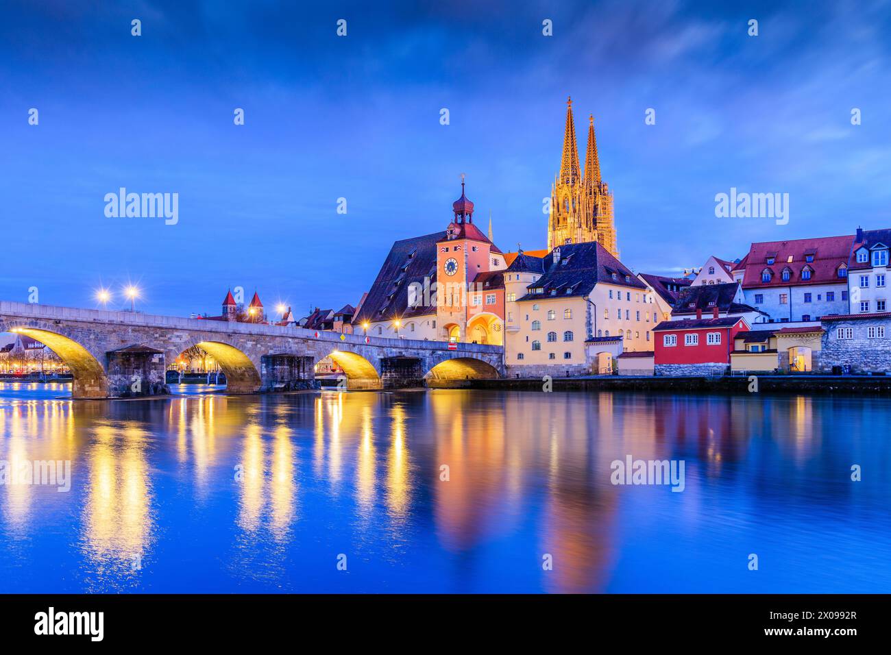 Regensburg, Bayern, Deutschland. Kathedrale von St. Peter und die Steinerne Brücke über die Donau bei Nacht. Stockfoto