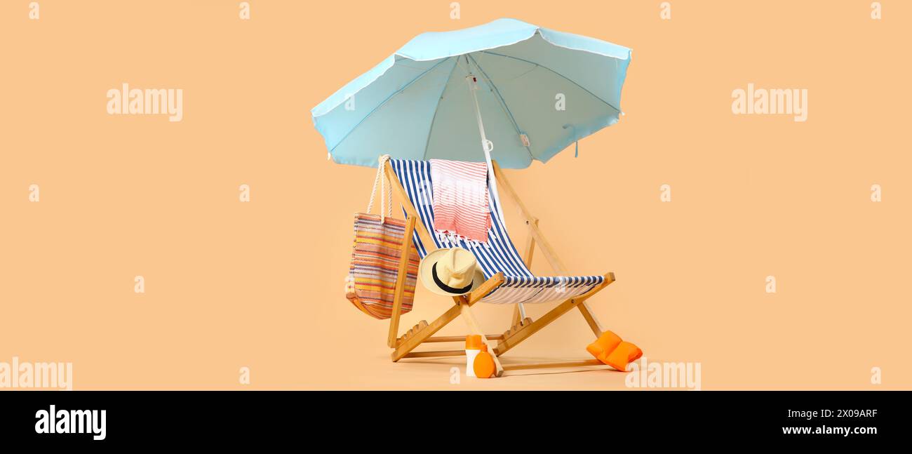 Liegestuhl, Sonnenschirm und Strandaccessoires auf beigefarbenem Hintergrund Stockfoto