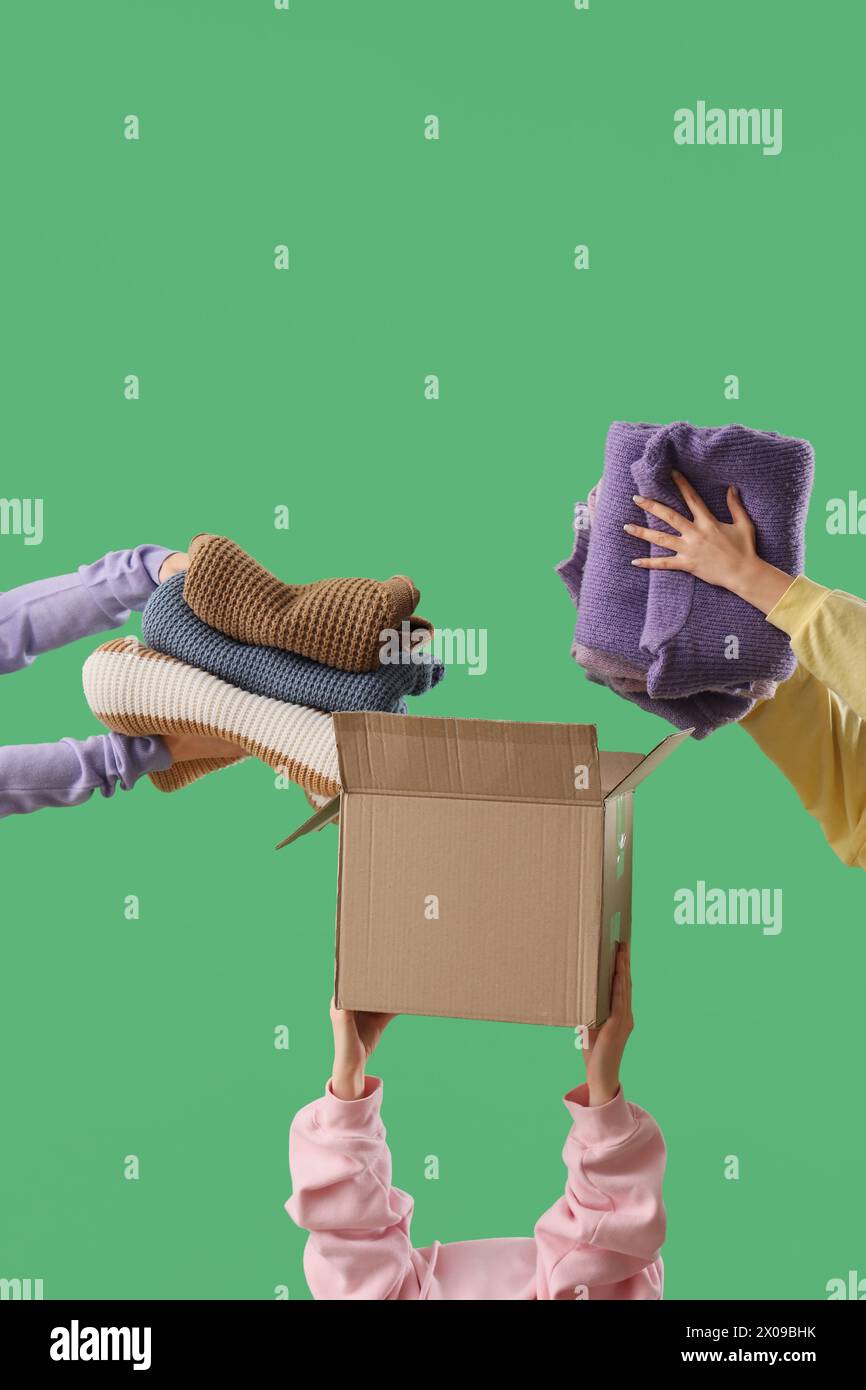 Frauen packen Kleidung in Umzugskarton auf grünem Hintergrund Stockfoto