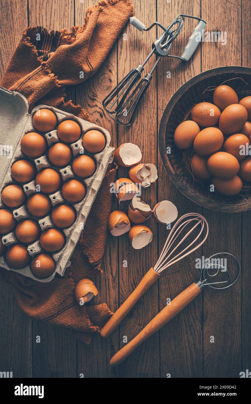 Frische Bio-Eier mit Küche und Backutensilien auf Holztisch Stockfoto