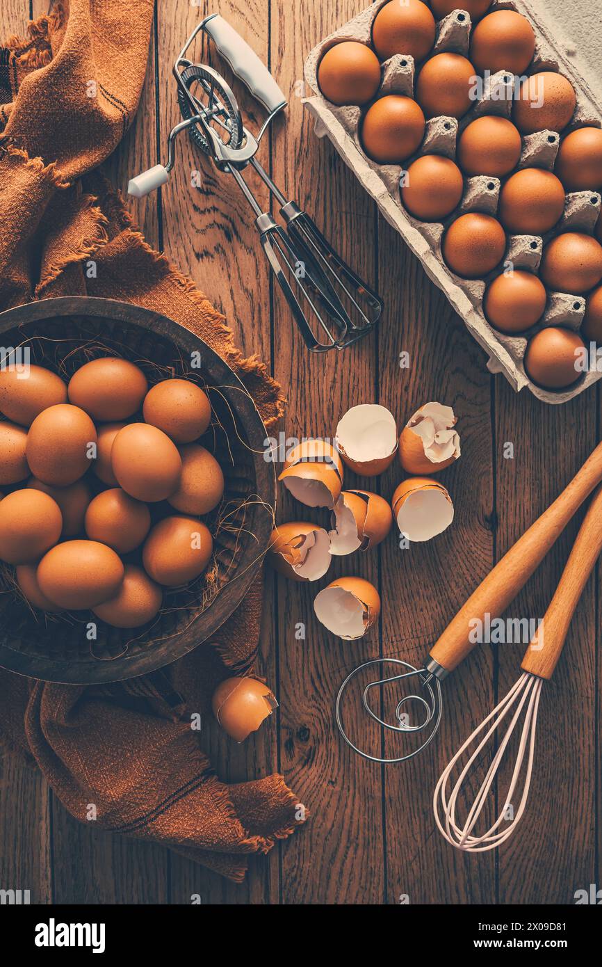 Frische Bio-Eier mit Küche und Backutensilien auf Holztisch Stockfoto