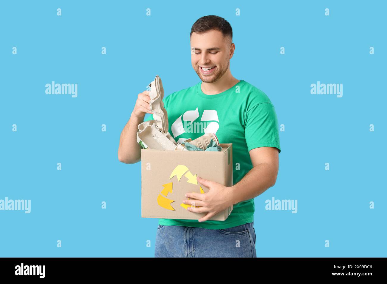Männlicher Freiwilliger mit Recyclingbox auf blauem Hintergrund Stockfoto