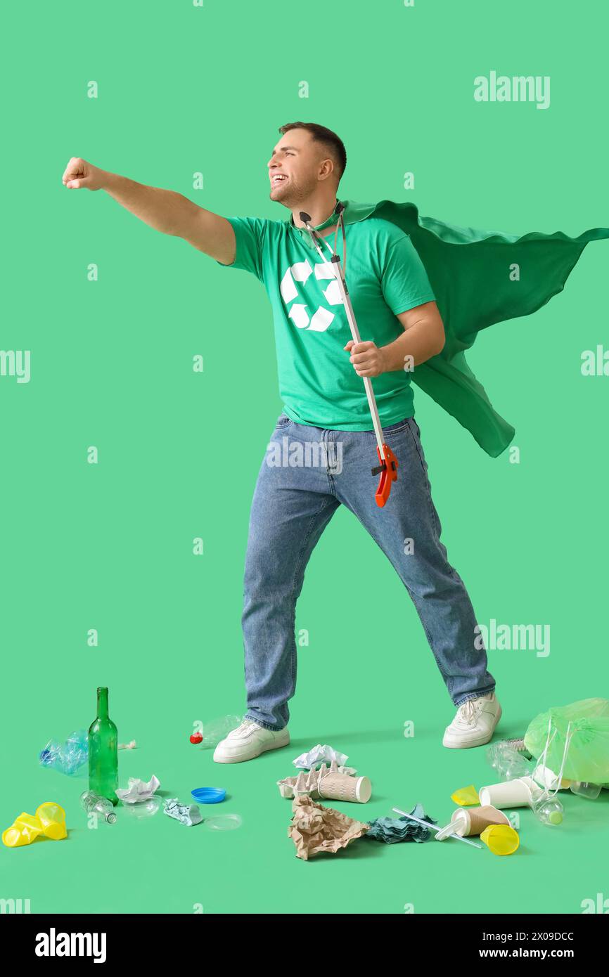 Männlicher Freiwilliger im superheldencape mit Müllpflücker auf grünem Hintergrund Stockfoto