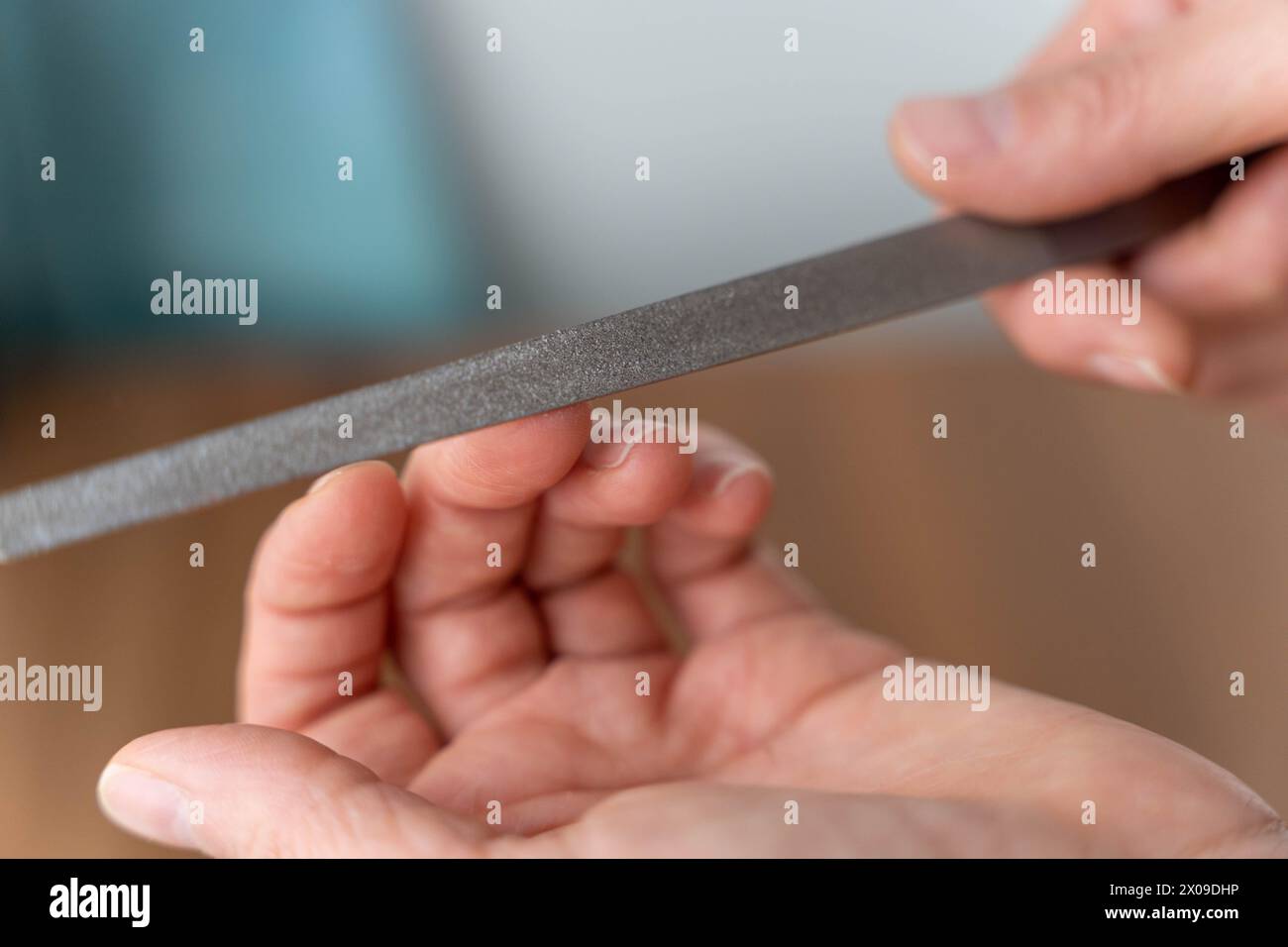 Detaillierte Nahaufnahme der Hände einer Frau, die einer professionellen Maniküre unterzogen wird, wobei der Schwerpunkt auf dem Feilprozess liegt, während die Nägel sorgfältig geformt und geformt sind Stockfoto