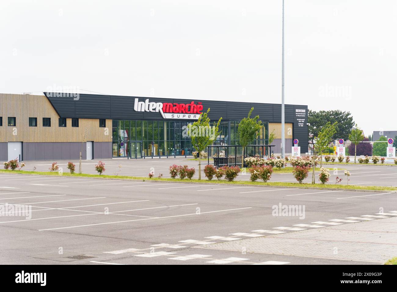 Cambrai, Frankreich - 21. Mai 2023: Die Fassade des Supermarktes Intermarche mit seiner markanten Beschilderung, flankiert von landschaftlich angelegtem Grün und einem weitläufigen Park Stockfoto