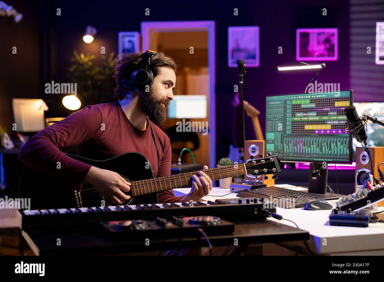Musiktechniker spielt neue Melodien auf Akustikgitarre und nimmt mit der daw-Software-Schnittstelle auf, bereitet sich auf die Mischen- und Mastering-Session vor. Junger Songwriter, der Soundtracks mit Instrument erstellt. Stockfoto