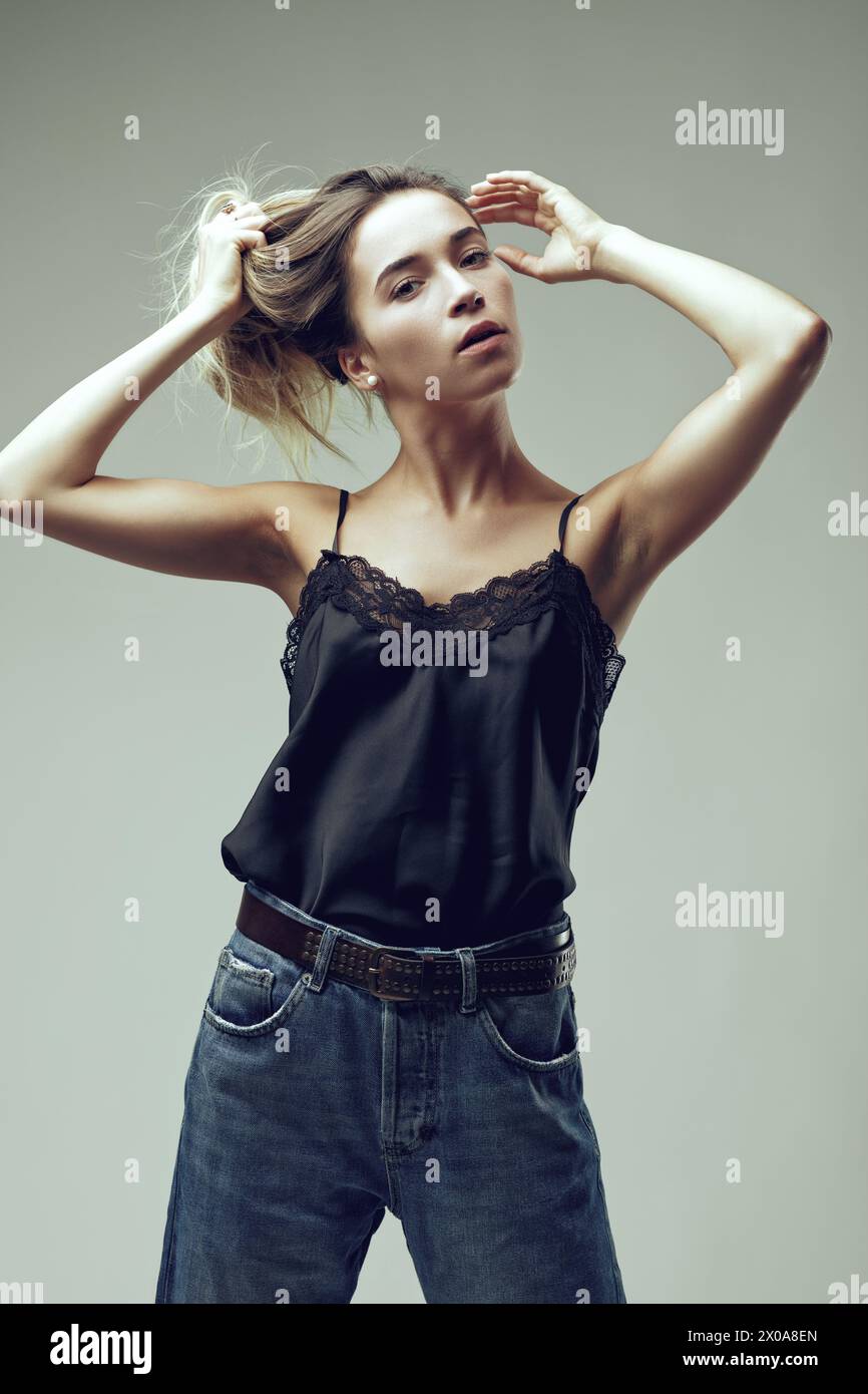 Die Frau fängt einen ehrlichen Moment ein und bindet ihre Haare, ihre Kleidung aus Spitze und Denim, die lässige Eleganz vermittelt Stockfoto