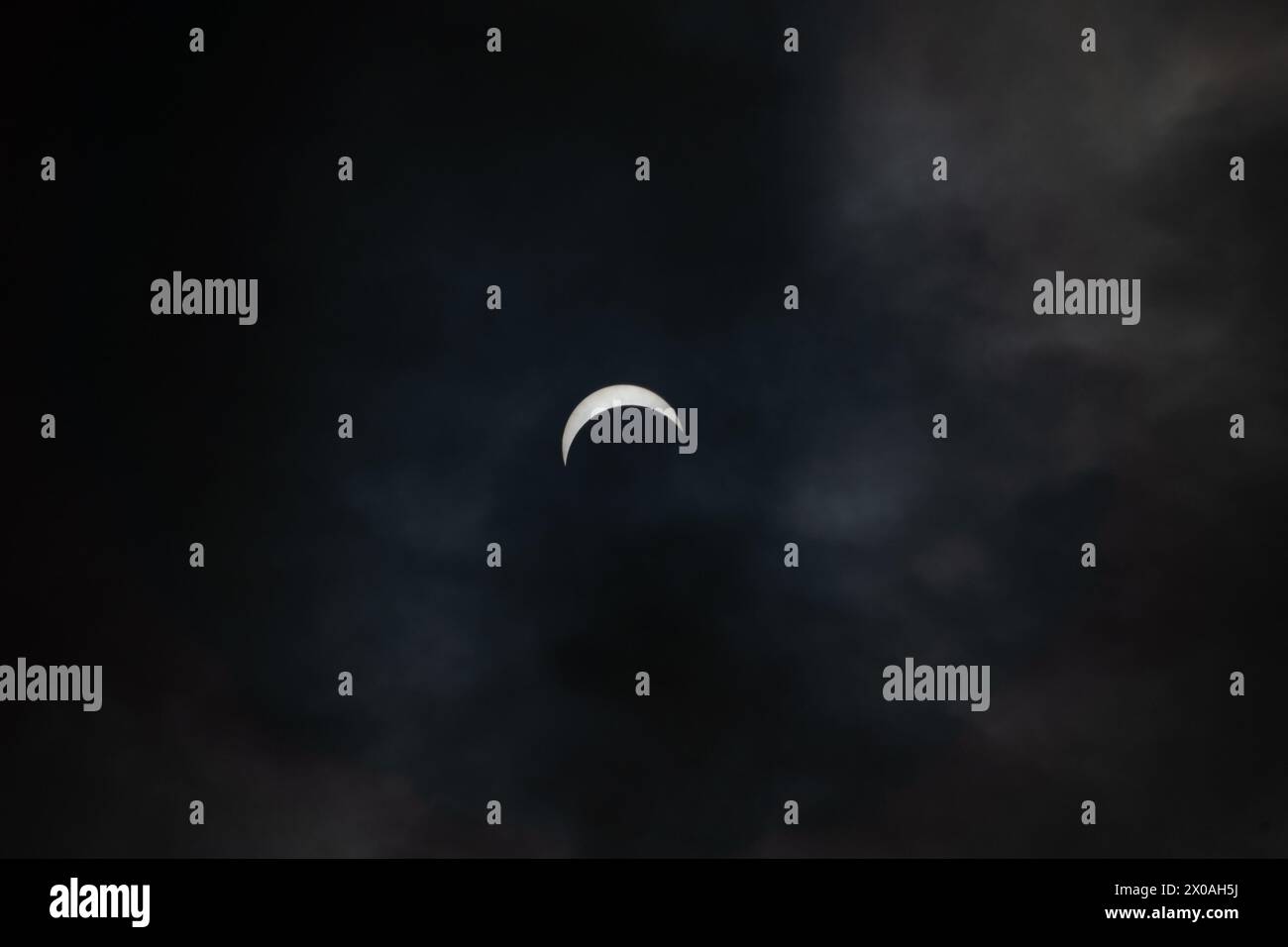 Partielle Sonnenfinsternis - Mond bedeckt Sonne, dunkle Wolken, himmlisches Drama - Halbmondsonne - atmosphärische Stimmung. Aufgenommen in Toronto, Kanada. Stockfoto