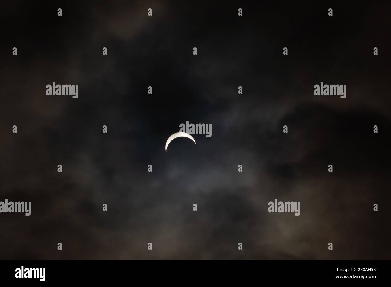 Partielle Sonnenfinsternis - Mond bedeckt Sonne, dunkle Wolken, himmlisches Drama - Halbmondsonne - atmosphärische Stimmung. Aufgenommen in Toronto, Kanada. Stockfoto