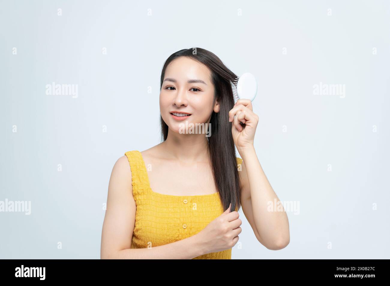 Wunderschöne asiatische Frau, die ihr gesundes Haar putzt Stockfoto