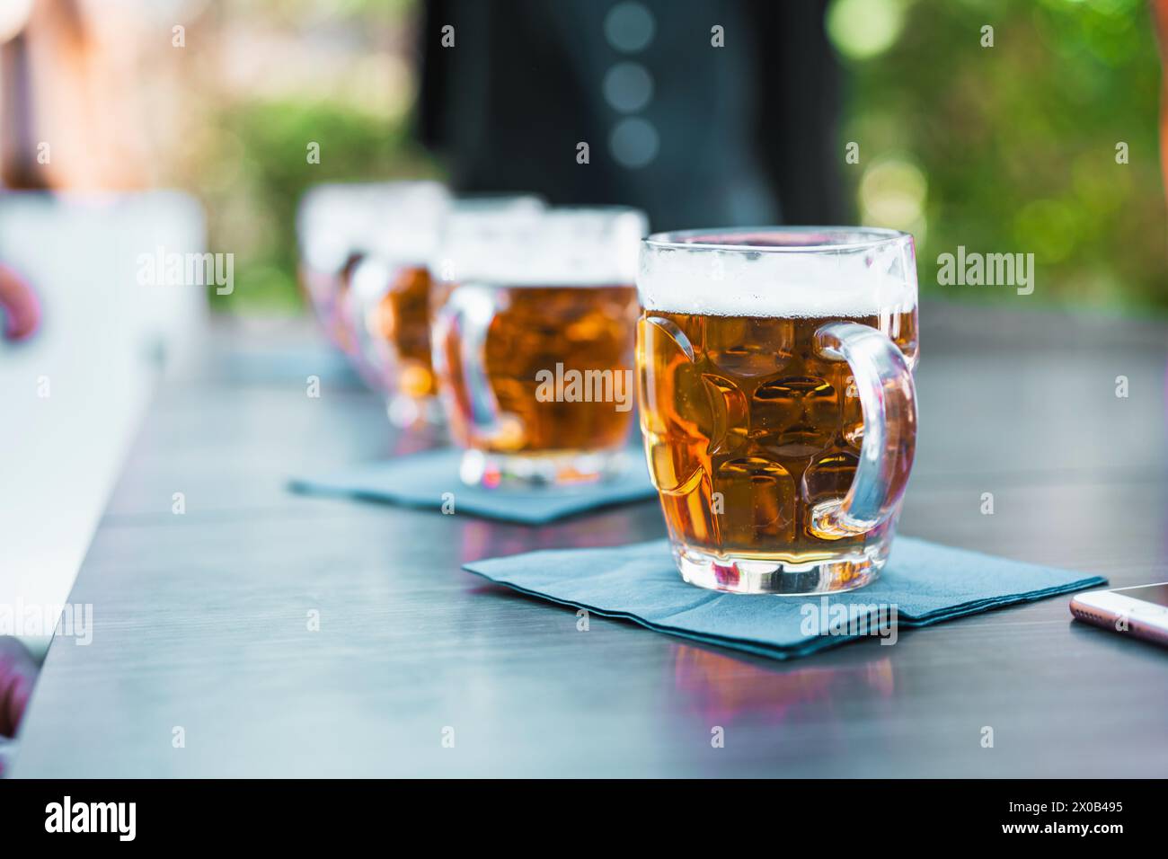 Reihe von Biergläsern auf einem Tisch im Freien - Biergeschmack erfrischende Momente unter freiem Himmel, die das Wesen der sozialen Freizeit einfangen. Stockfoto