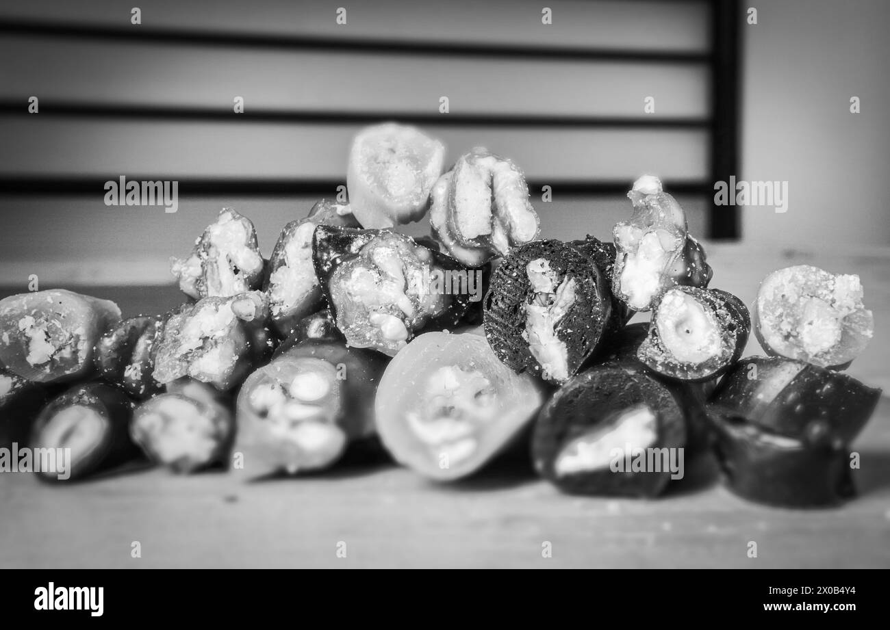 Schwarzweiß-Makroaufnahme verschiedener Arten von geschnittenen Friedensstücken von Churchkhela mit Hintergrund des Bankraumes. Georgianisches Obst-Snacks-Konzept. Stockfoto