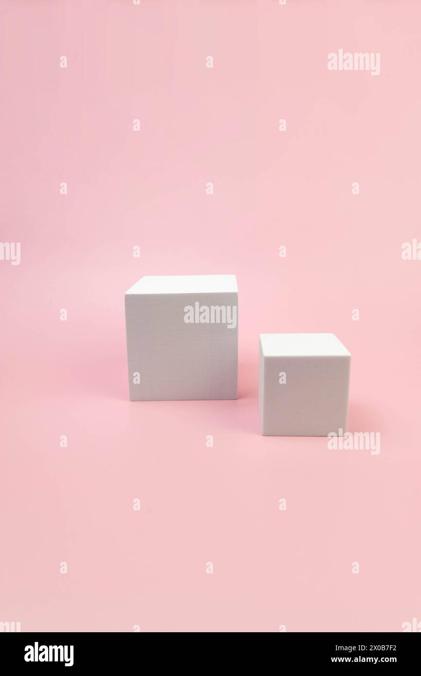 Weißes quadratisches Podium auf rosafarbenem Hintergrund. Geometrische abstrakte Formen für die kosmetische Produktpräsentation. Zwei verschiedene Größen, quadratische Formen. Kopierbereich. Stockfoto