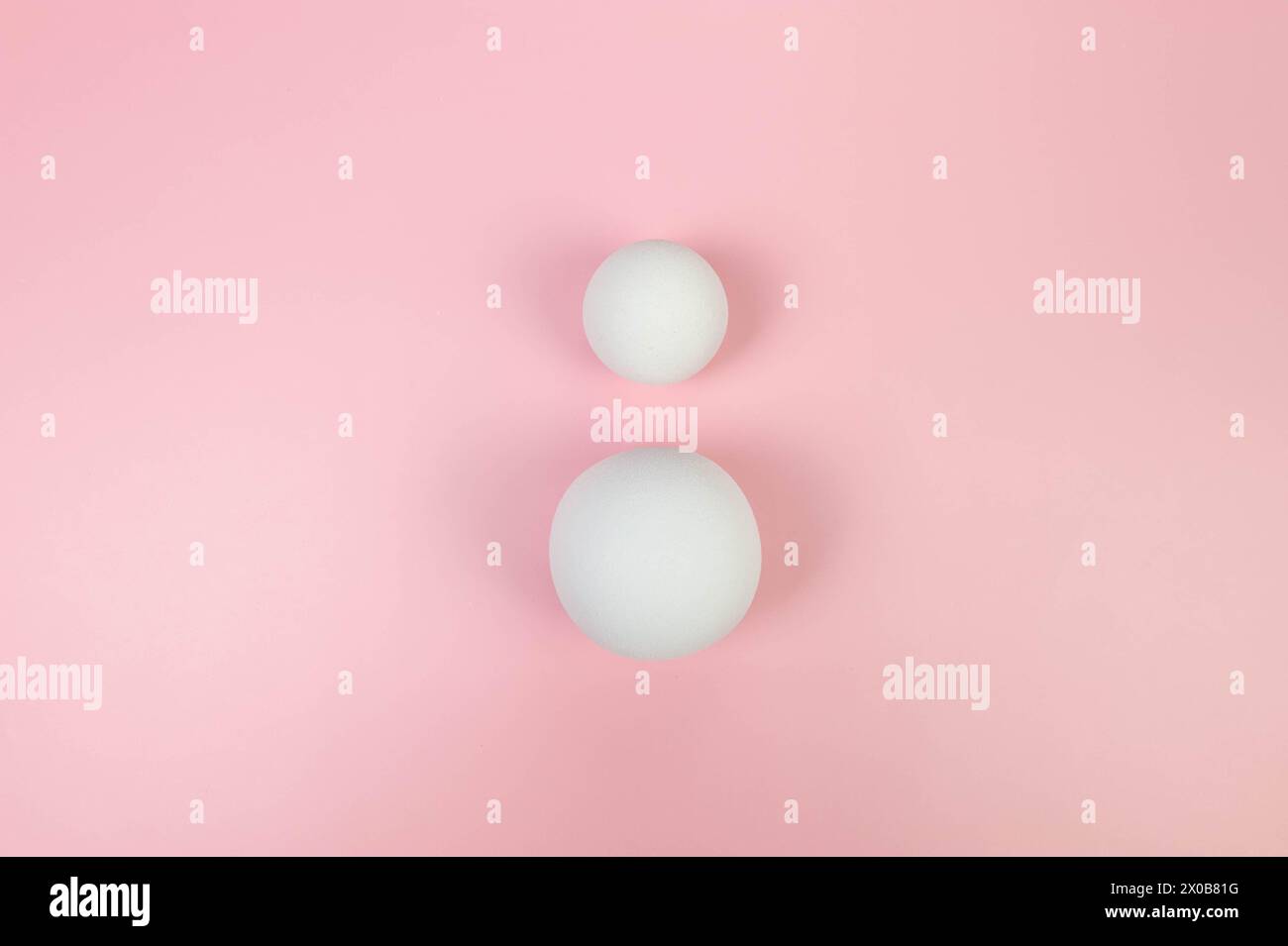 Draufsicht von zwei weißen Kugeln auf rosafarbenem Hintergrund. Geometrische abstrakte Formen für die kosmetische Produktpräsentation. Flache Ladefläche, Kopierraum. Stockfoto