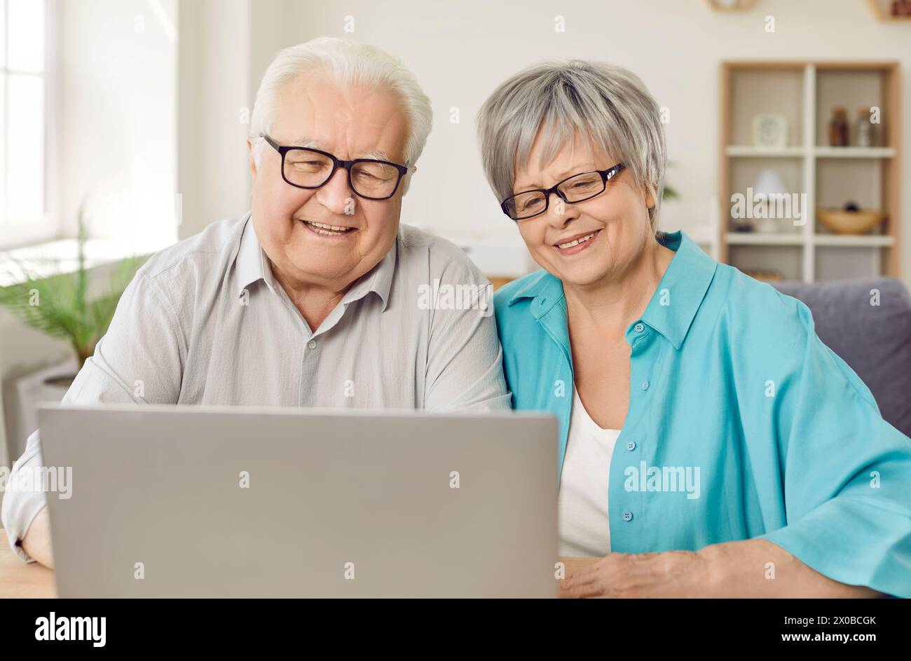 Fröhliches älteres Ehepaar im Ruhestand, das einen Laptop zum Anschauen von Filmen, zum Online-Shopping und für Videoanrufe benutzt. Stockfoto
