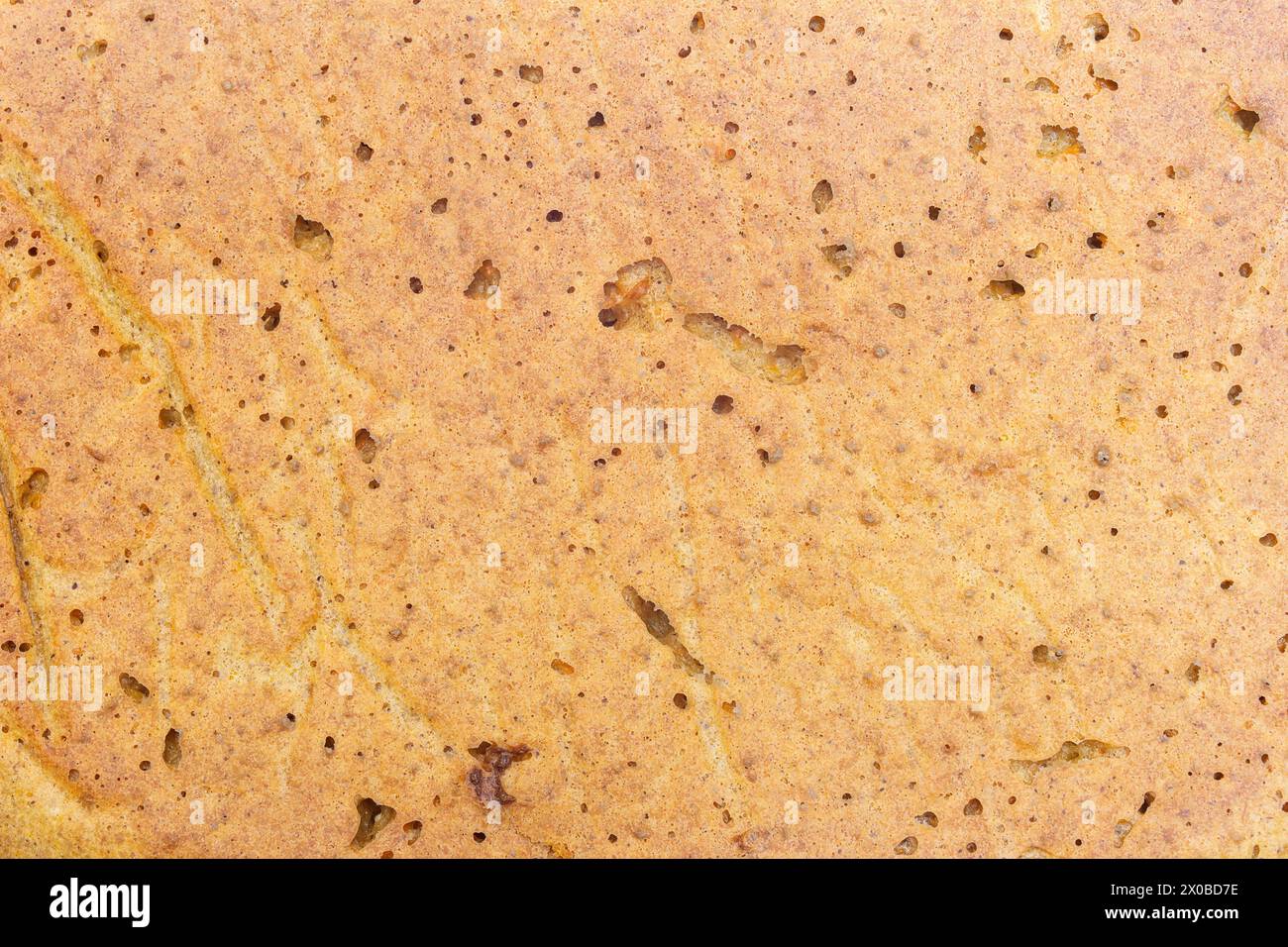 Blick von oben auf einen Kuchen mit einer warmen, beigen, bröckeligen Textur, mit dunklen Flecken gepunktet und durch hellere Streifen hervorgehoben. Hausgemachte Essenz von gebackenem Abendessen Stockfoto