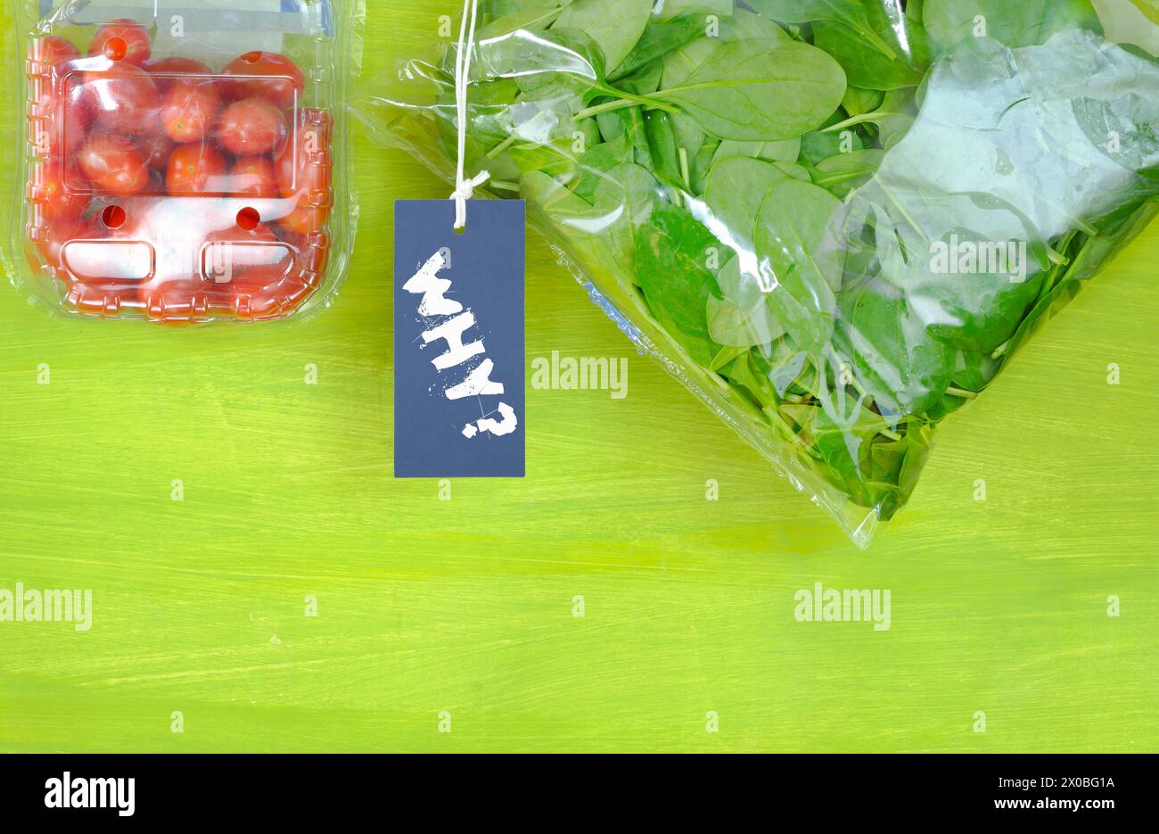Plastikverpacktes Essen, Spinat und Tomaten in Plastiktüten, Schild mit Unterschrift Warum? Umweltschutz, Vermeidung von Kunststoffverpackungen Stockfoto