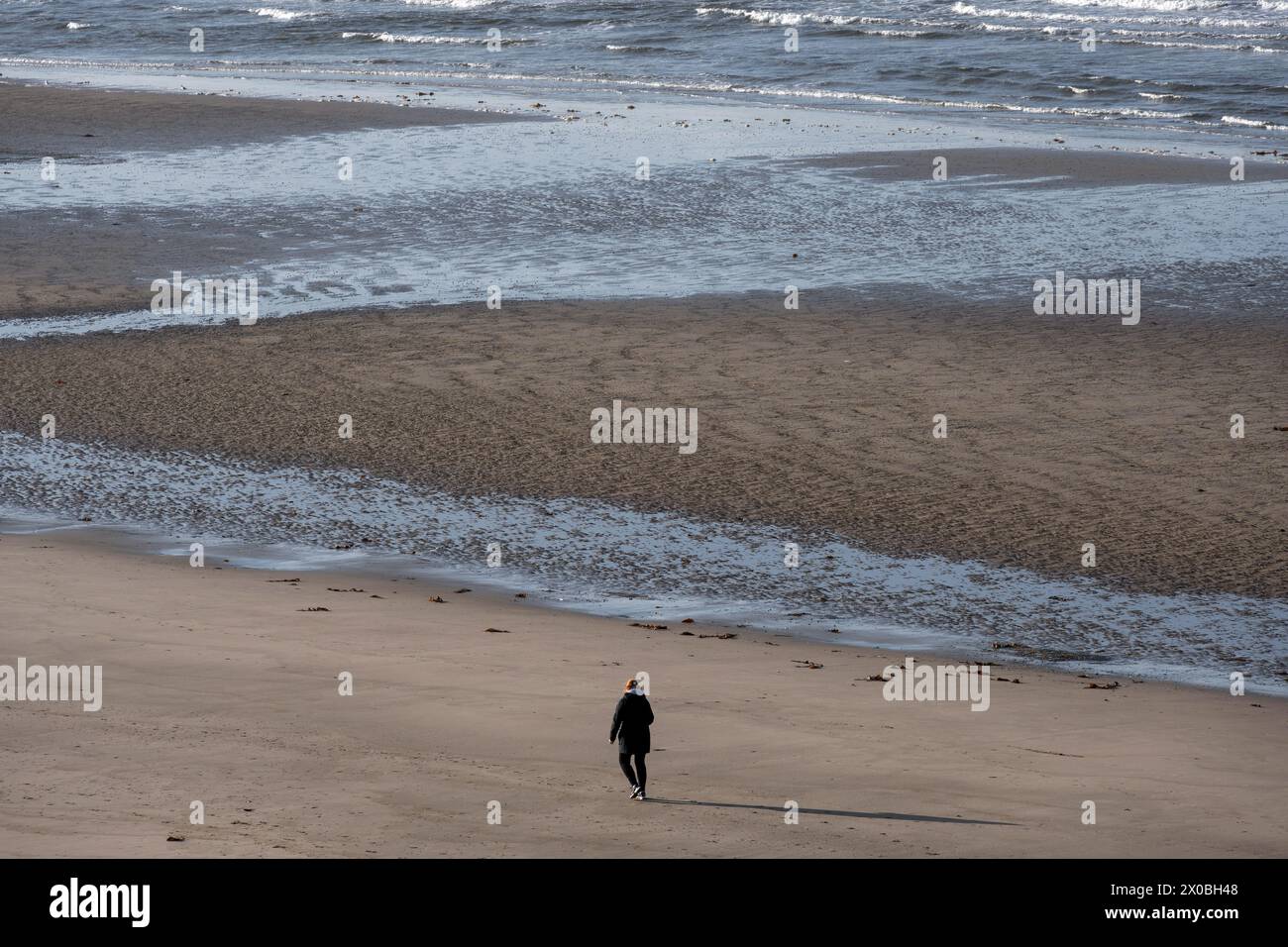 Eine Frau läuft allein am Sandstrand. Stockfoto