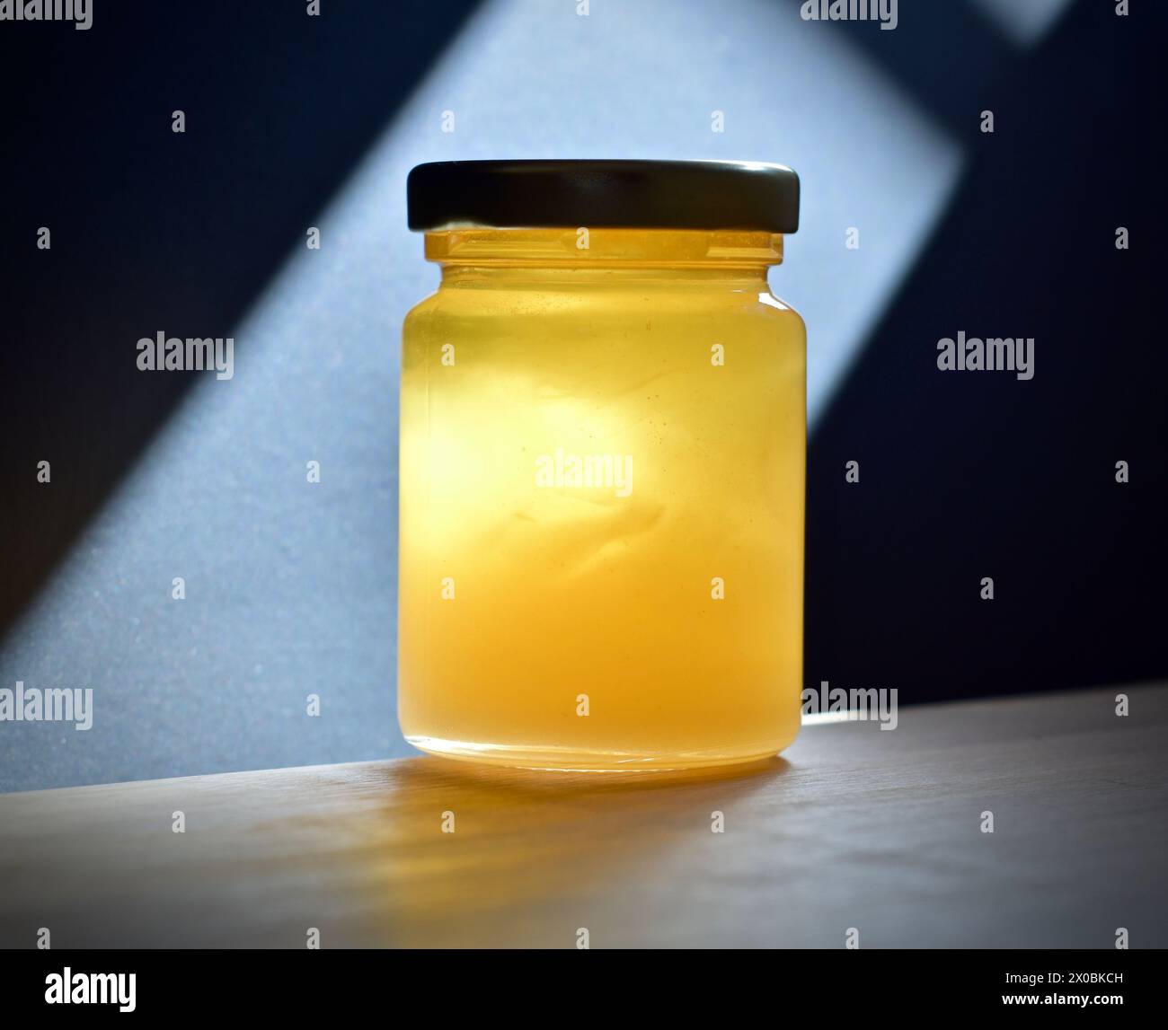 Glas Rosmarinhonig auf einem Tisch und Rosmarinzweig auf hellem Hintergrund Stockfoto