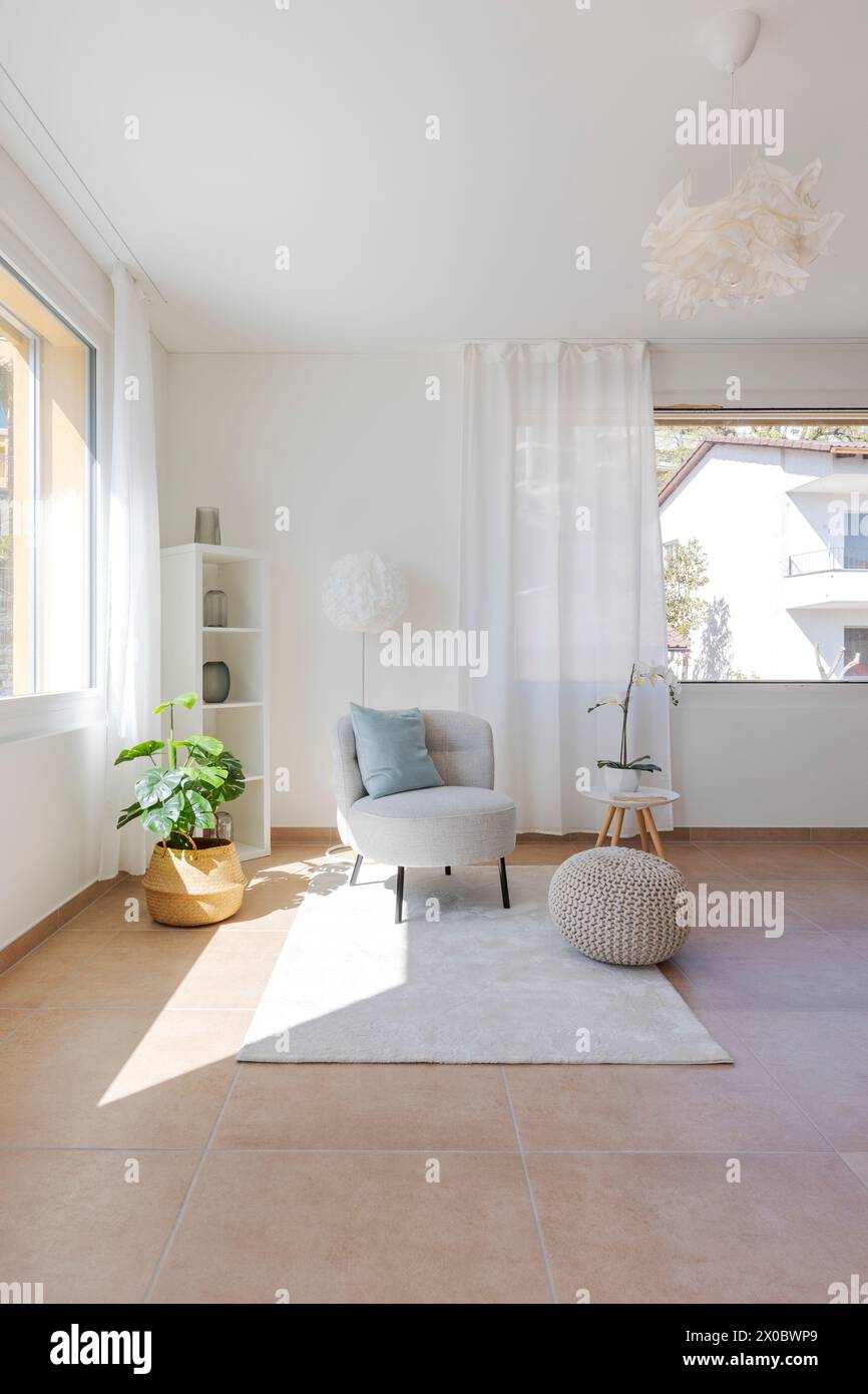Detail einer Wohnzimmerecke mit einem kleinen Sessel mit einem Couchtisch und einem Hocker auf dem Teppich. Niemand drinnen Stockfoto