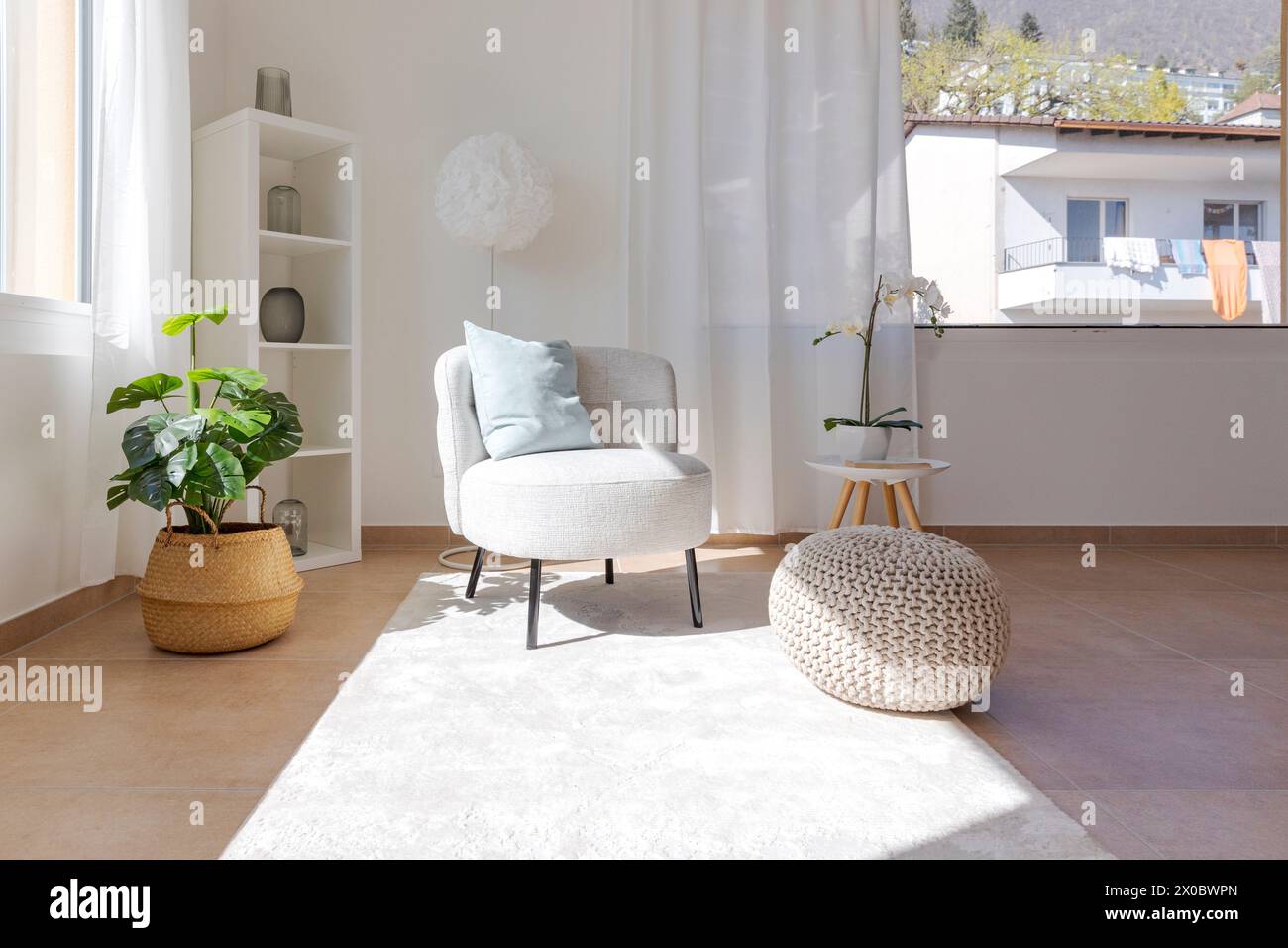 Detail einer Wohnzimmerecke mit einem kleinen Sessel mit einem Couchtisch und einem Hocker auf dem Teppich. Niemand drinnen Stockfoto