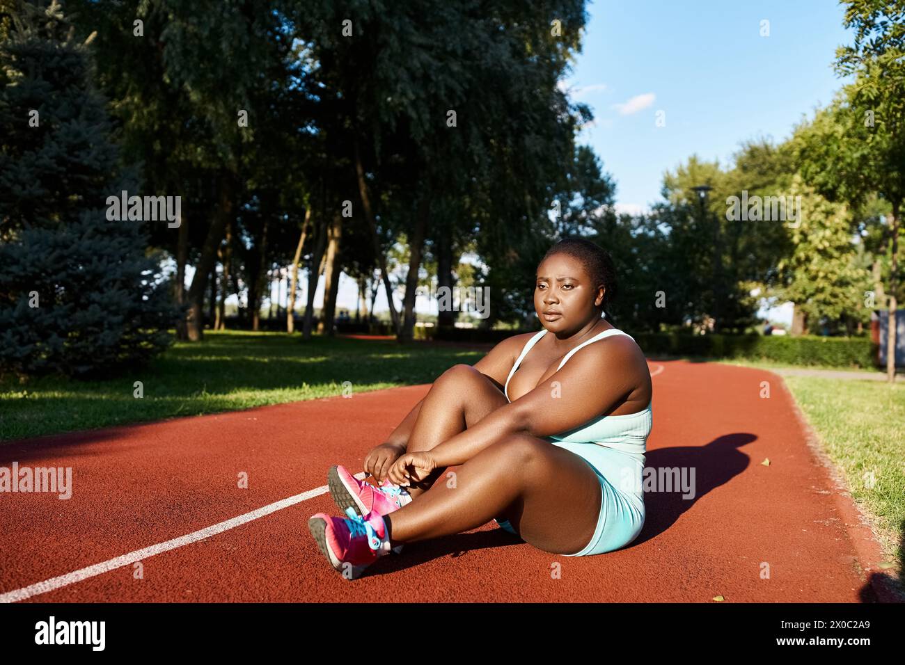 Eine Afroamerikanerin in Sportbekleidung sitzt auf dem Tennisplatz und macht eine Pause vom Sport im Freien. Stockfoto