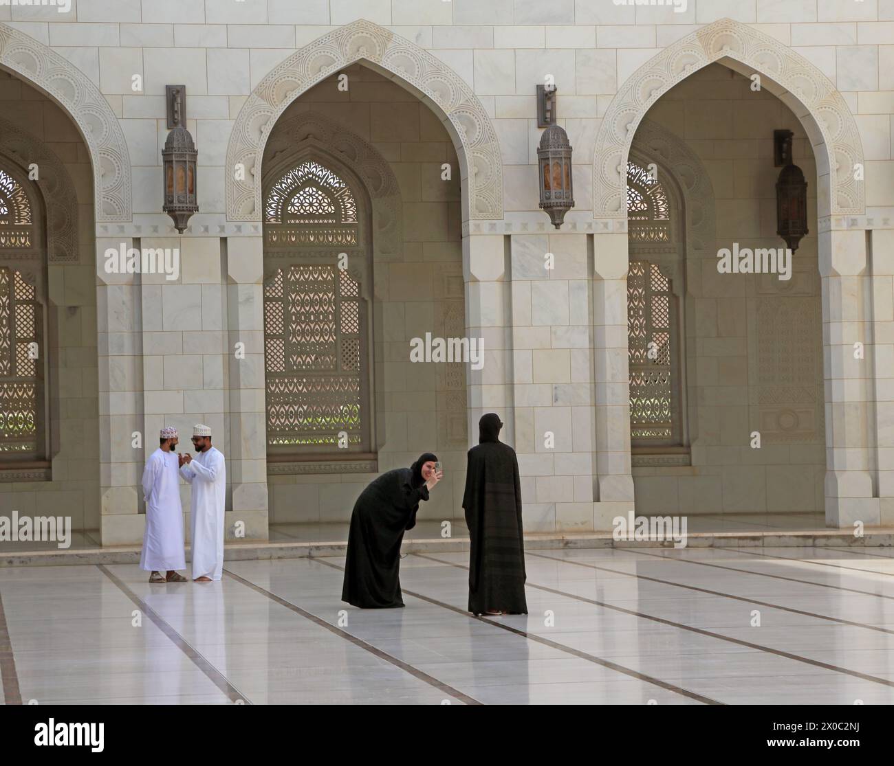 Besucher der Sultan Qaboos Grand Moschee fotografieren mit dem Smartphone im Innenhof (Sahn) Muscat Oman Stockfoto