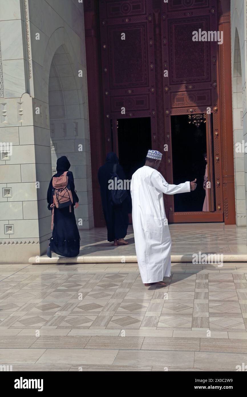 Sultan Qaboos große Moschee Omani mit Dishdasha und Kummah, die durch eine Holztür betreten, Muscat Oman Stockfoto