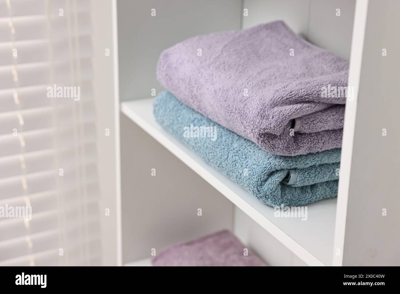 Gestapelte Handtücher im Regal drinnen. Leerzeichen für Text Stockfoto