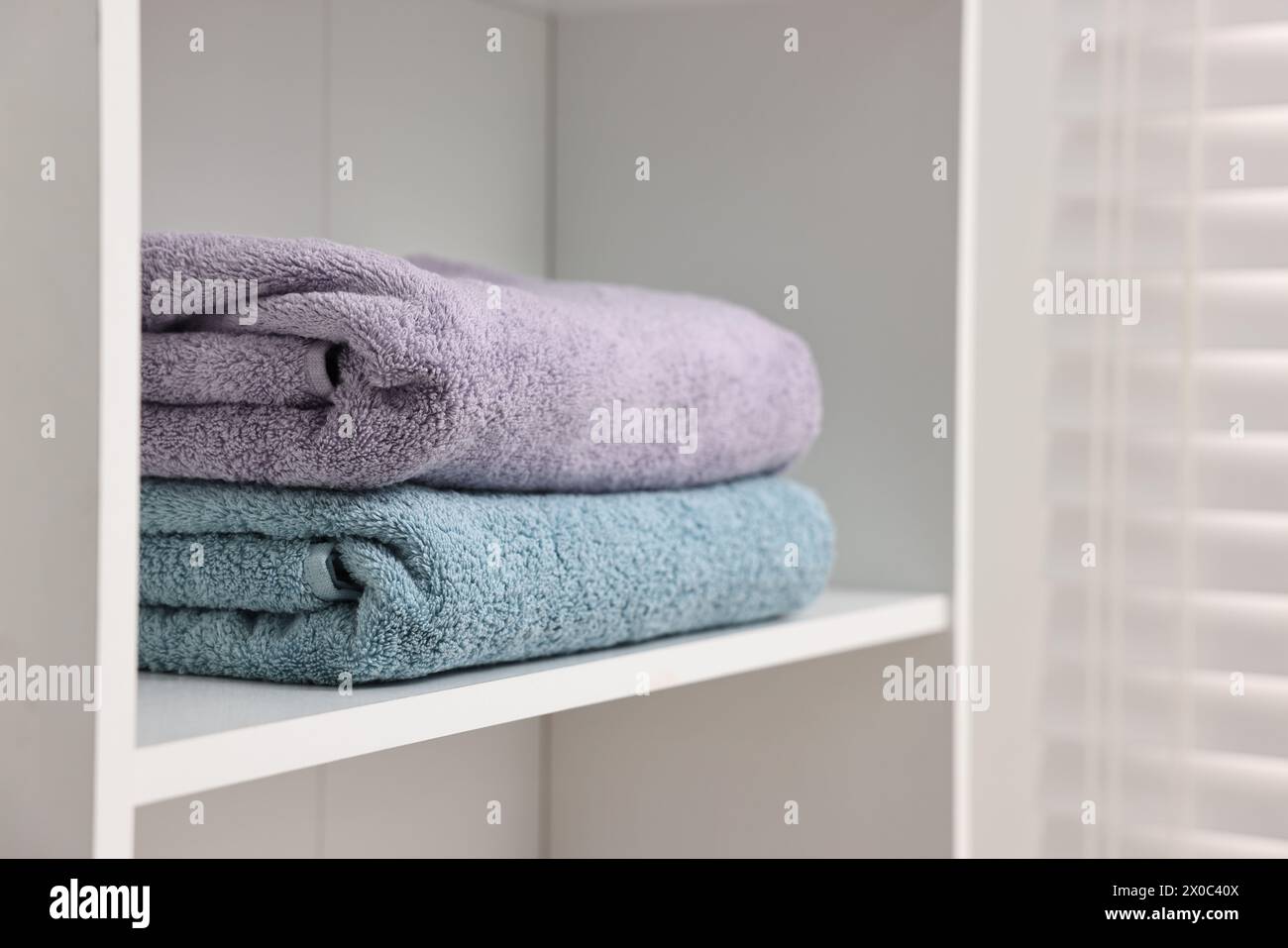 Gestapelte Handtücher im Regal drinnen. Leerzeichen für Text Stockfoto