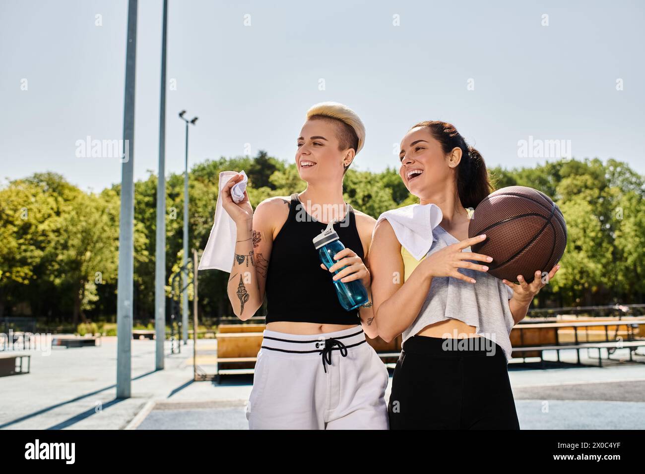 Zwei sportliche Freundinnen stehen zusammen und halten Basketbälle im Sommer im Freien. Stockfoto