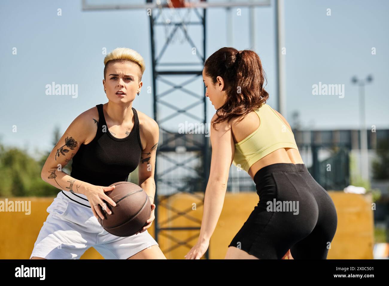 Zwei sportliche Freundinnen stehen Seite an Seite und halten im Sommer draußen Basketball. Stockfoto