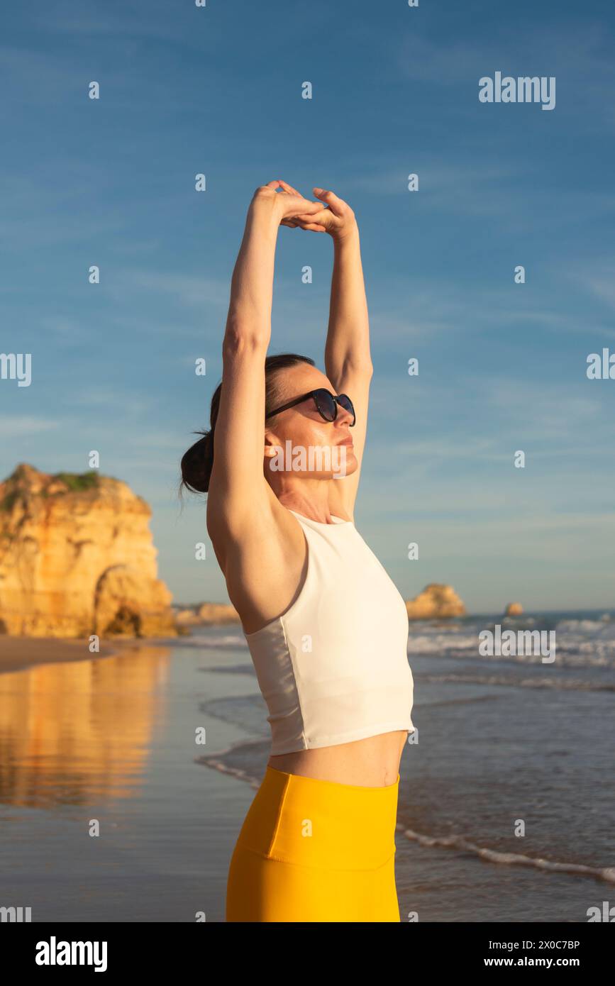 Frau, die inneren Frieden findet und sich in der Sonne am Strand ausdehnt. Stockfoto