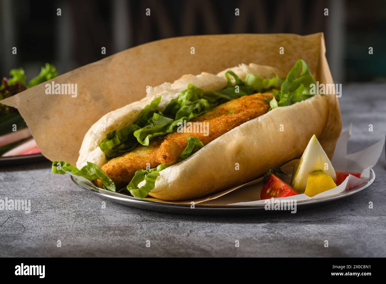 Gebratenes Fisch-Sandwich mit Gemüse auf dem Steintisch. Türkischer Name Balik Ekmek Stockfoto