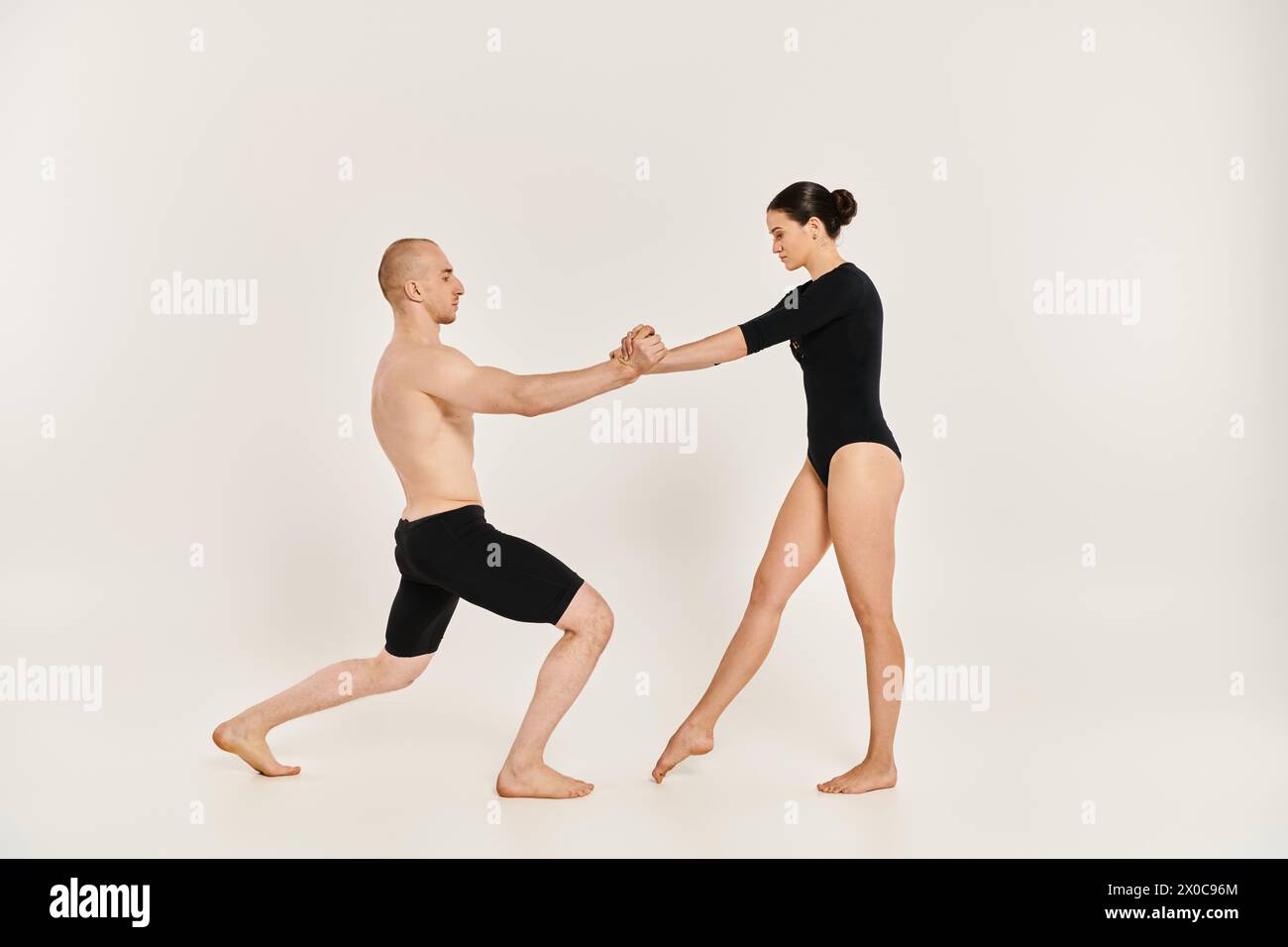 Ein akrobatischer junger Mann und eine akrobatische Frau tanzen elegant zusammen in einem Studio und zeigen ihre anmutigen Bewegungen. Stockfoto