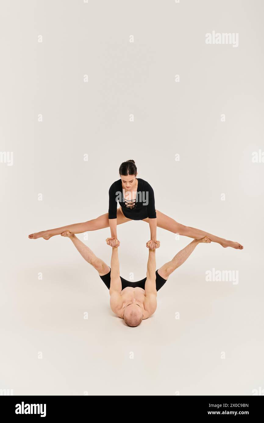 Eine Frau zeigt Stärke und Gleichgewicht, indem sie synchronisierte Handstände in einem Studio vor weißem Hintergrund vorführt. Stockfoto