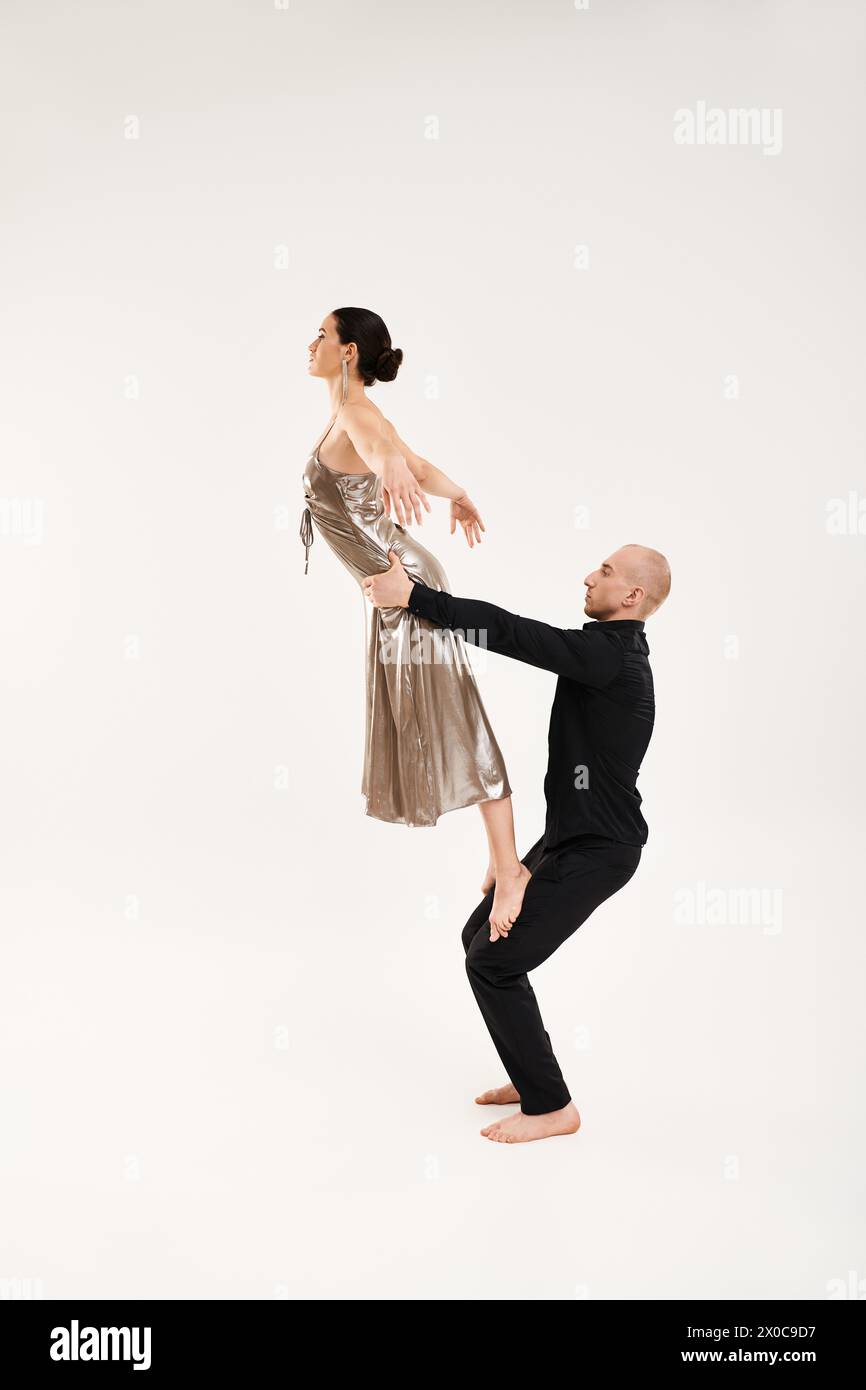 Junger Mann und Frau in schwarz gekleidet, spielen akrobatische Tanzbewegungen auf weißem Boden in einem Studio-Setting. Stockfoto