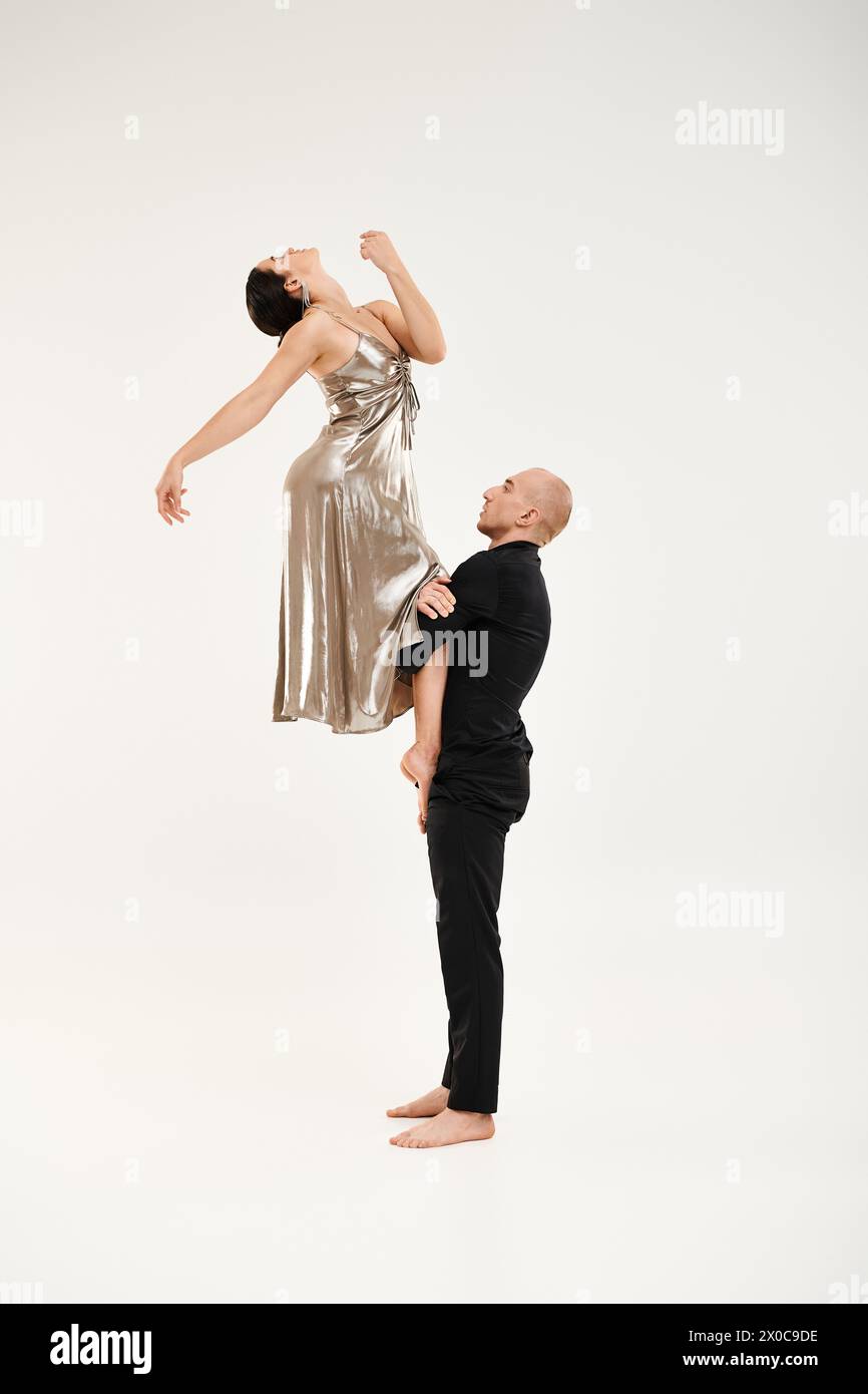 Ein junger Mann und eine Frau in einem silbernen Kleid, die sich in einer anmutigen Tanzroutine engagieren und ihre synchronisierten Bewegungen und akrobatischen Fähigkeiten demonstrieren. Stockfoto