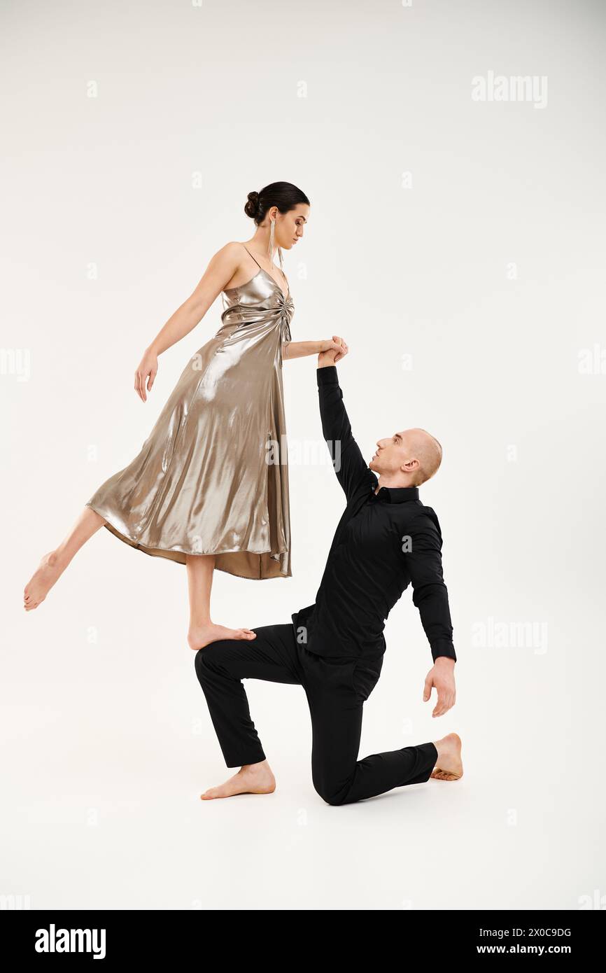 Ein junger Mann in Schwarz und eine junge Frau in einem Kleid tanzen anmutig zusammen, mit akrobatischen Elementen. Stockfoto