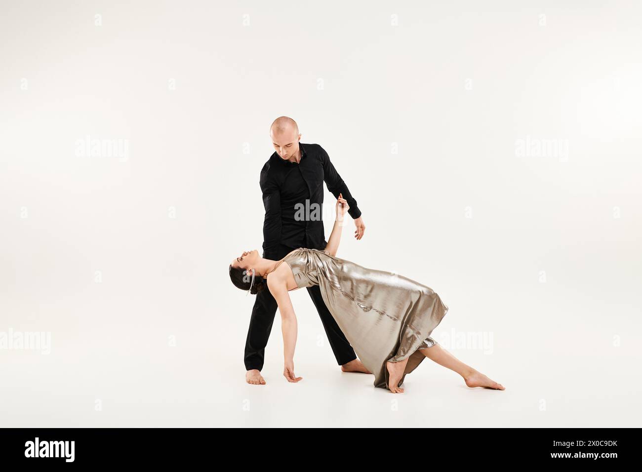 Ein junger Mann in Schwarz und eine junge Frau in einem Kleid tanzen als Paar mit akrobatischen Elementen. Studio auf weißem Hintergrund. Stockfoto