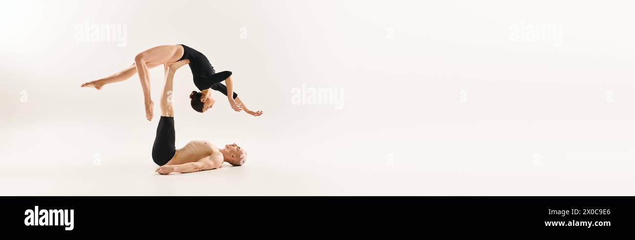 Eine Frau und ein Mann zeigen eindrucksvolle Balance, indem sie akrobatische Elemente machen. Stockfoto