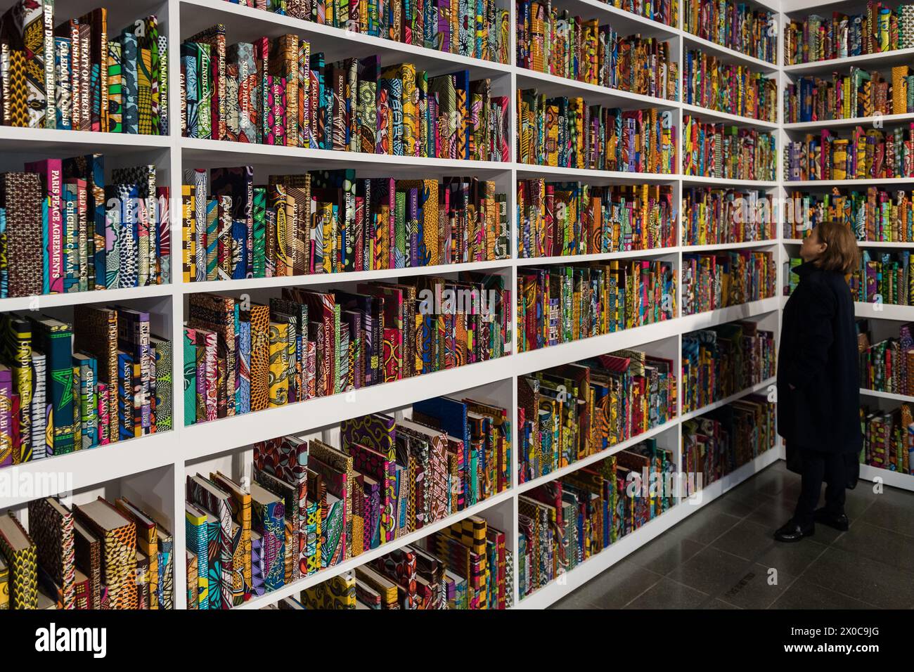 LONDON, VEREINIGTES KÖNIGREICH - 11. APRIL 2024: ein Besucher sieht eine neue großformatige Installation mit dem Titel „war Library“ (2024), die aus 5.000 Büchern besteht, die in holländischem Wachsdruck gebunden sind und Konflikte und Friedensverträge darstellen, während eines Fotoaufrufs für Yinka Shonibares Ausstellung „Suspended States“ am 11. April 2024 im Serpentine South in London, Großbritannien. Die erste Einzelausstellung von Shonibares Werk in einer öffentlichen Londoner Institution seit über 20 Jahren beschäftigt sich mit zentralen Themen des Vermächtnisses der Kolonialmacht, der Zuflucht- und Schutzorte sowie den ökologischen Auswirkungen der Kolonisierung, dem europäischen Erbe von i Stockfoto