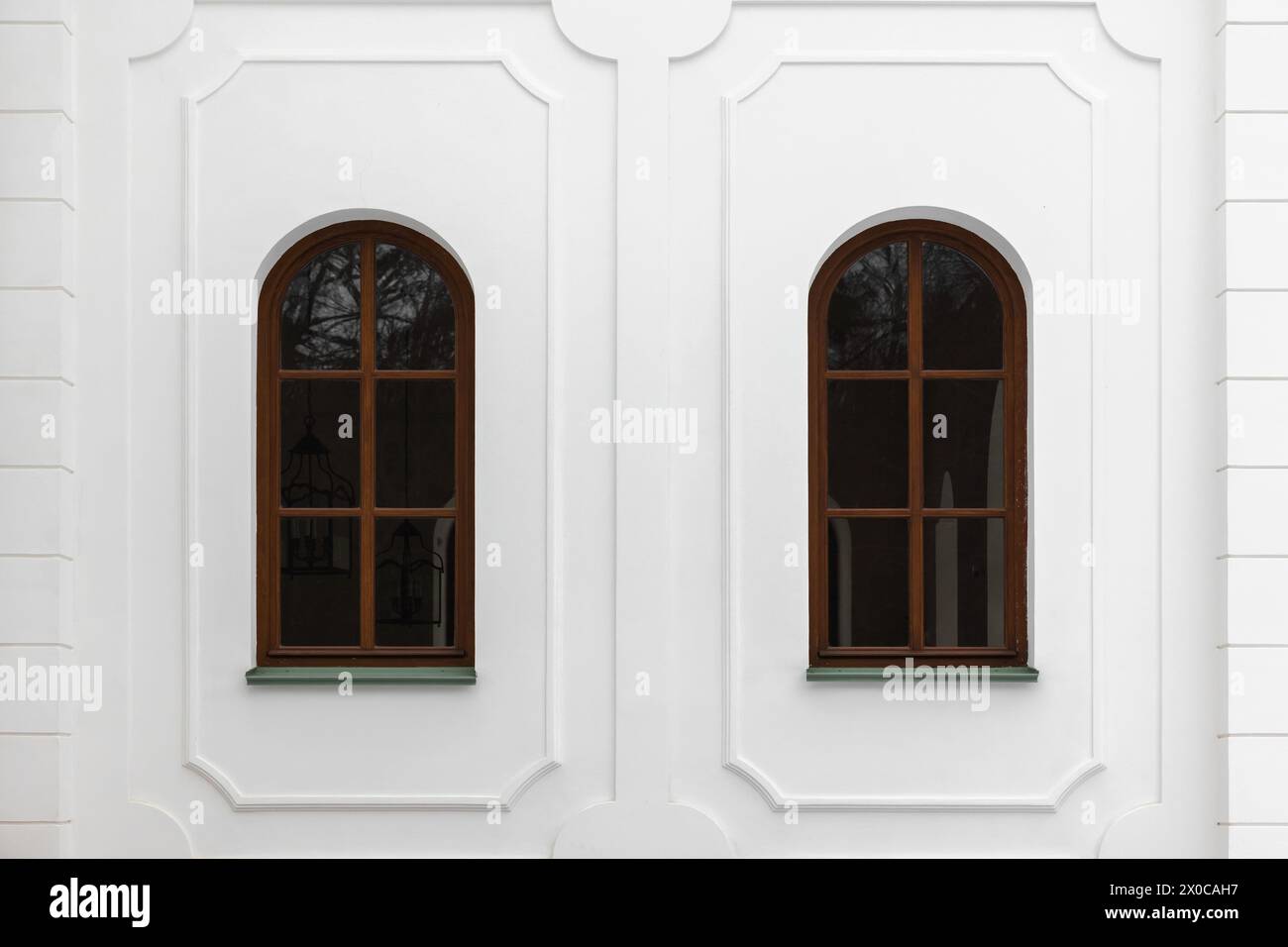 Klassische Fenster mit Bögen und dekorativen Elementen in weißer Steinmauer. Hintergrundfotostruktur Stockfoto